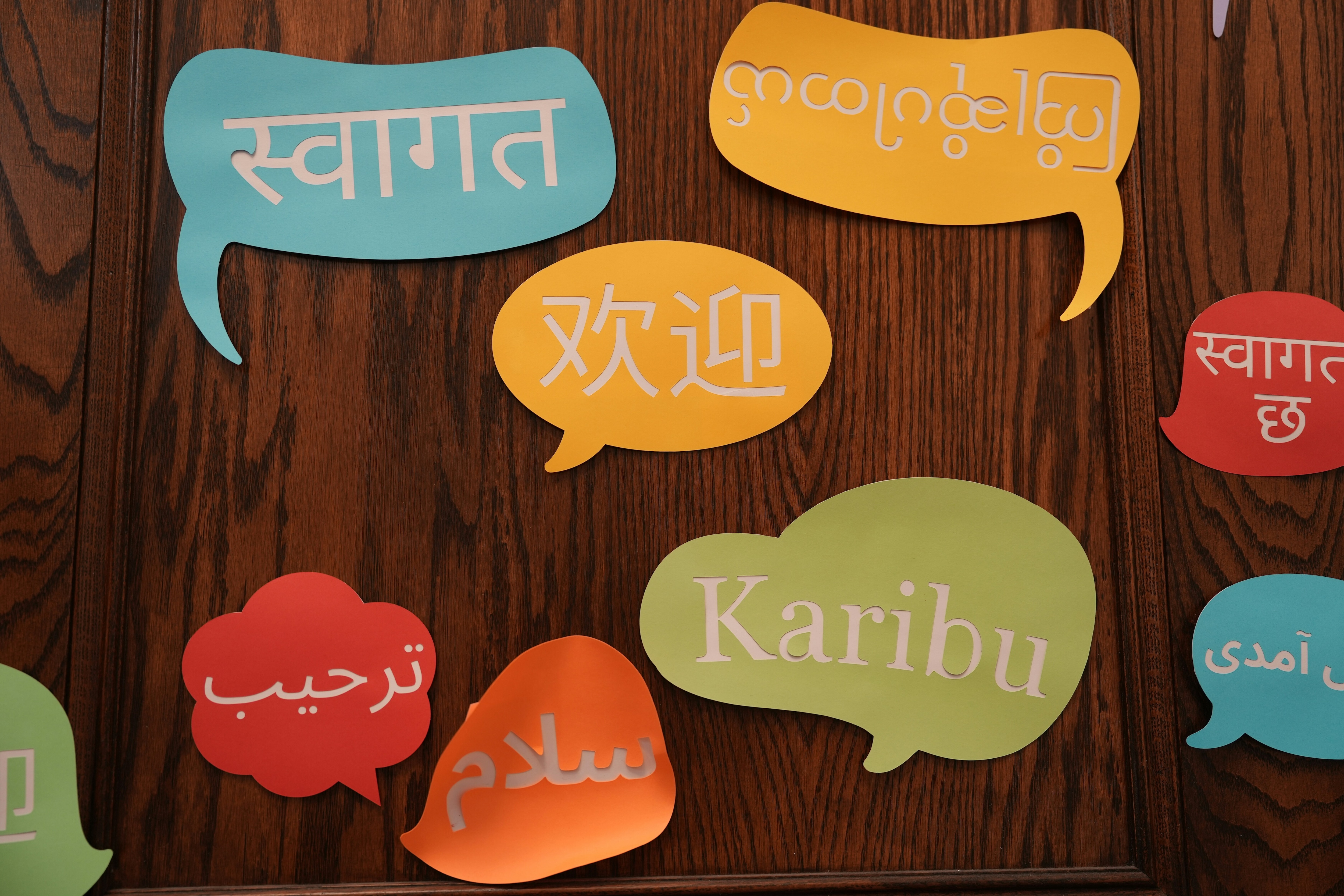 A group of colourful speech bubbles with different languages: AI agents must embrace diverse languages to avoid reinforcing inequalities