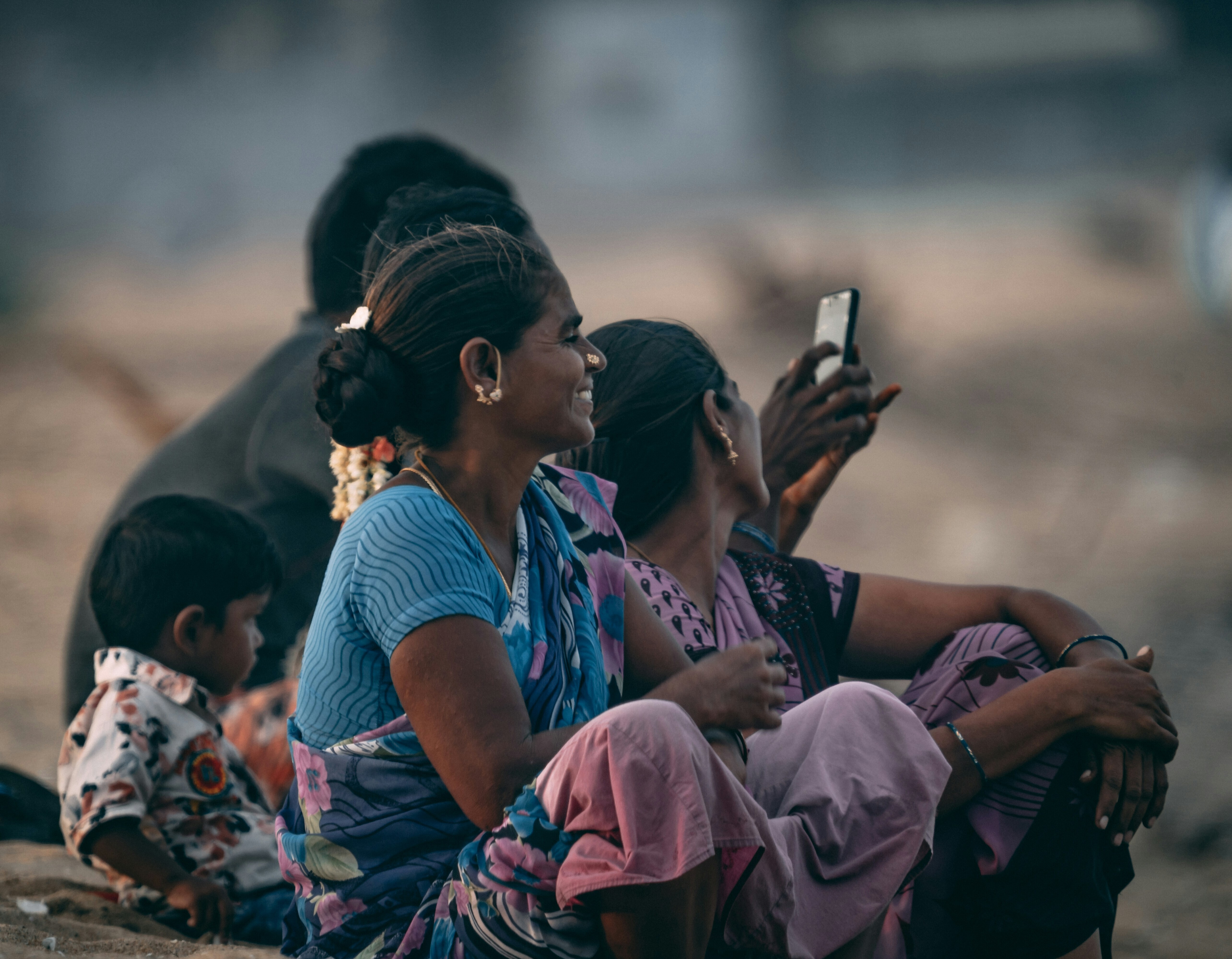 A family looking at a mobile phone on a beach in India