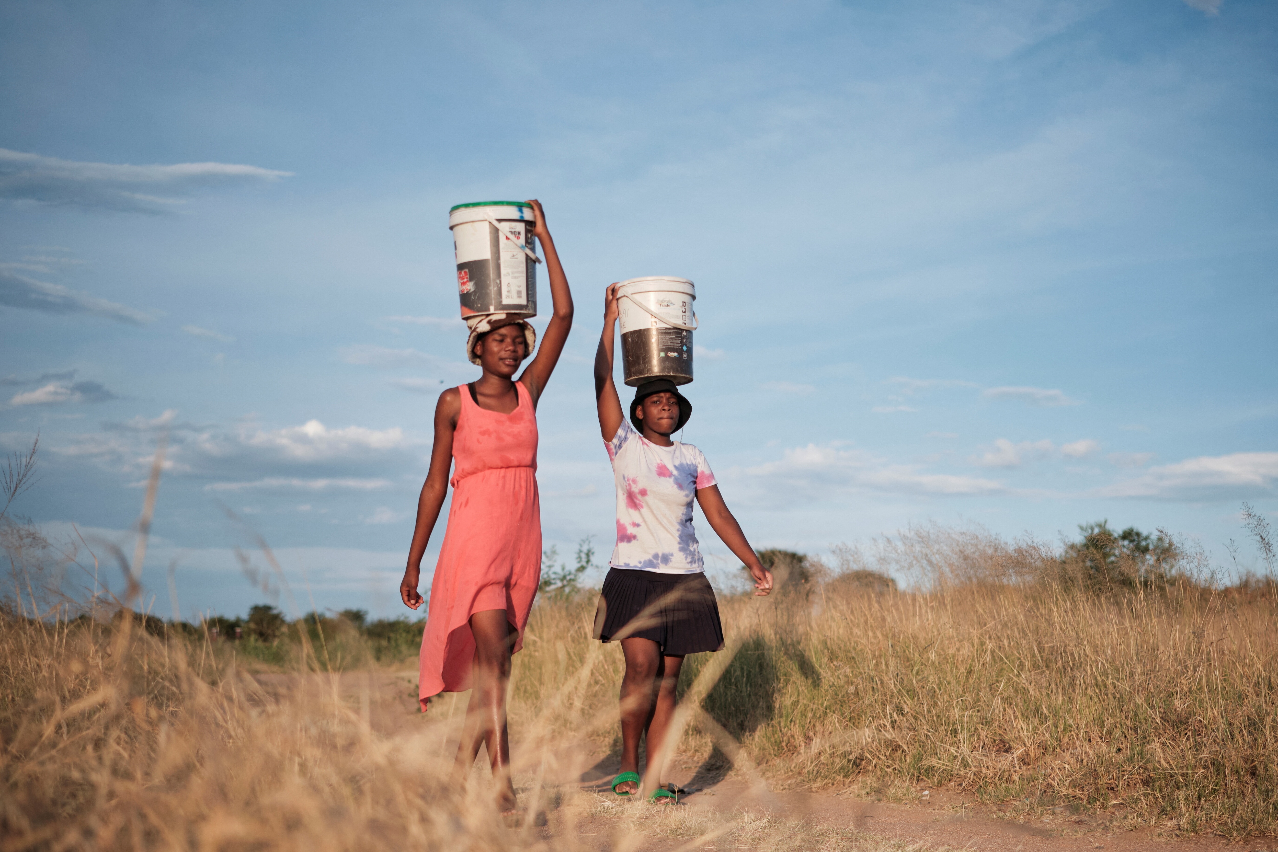 Residents of Pumula East township walk home after fetching water from a well, as temperatures soar during an El Niño-related heatwave and drought in Bulawayo, Zimbabwe in 2024. 
