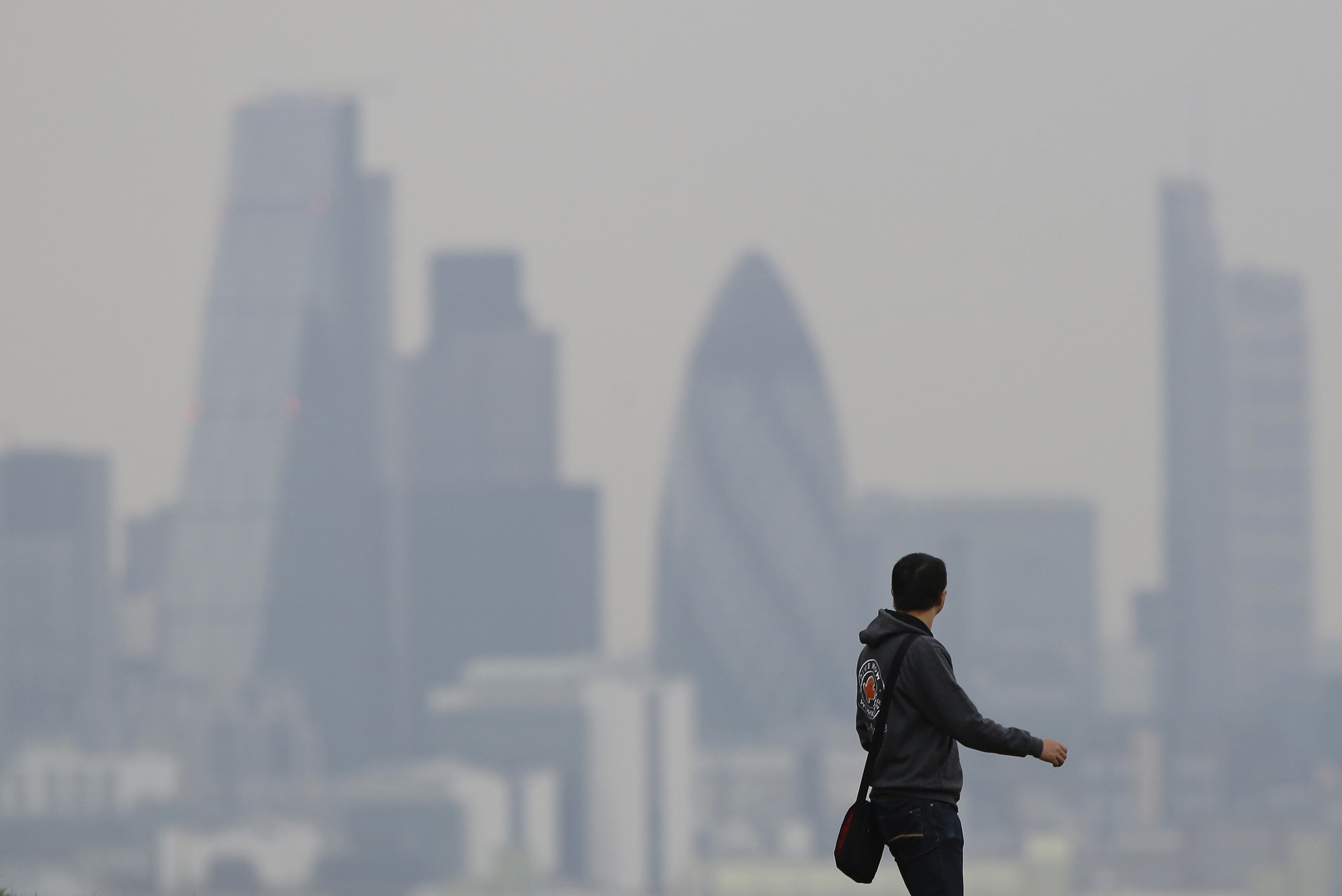 A man walks through Greenwich Park as a haze of pollution sits over the London skyline April 3, 2014:  The conversation on Scope 3 emissions is shifting to best approaches
