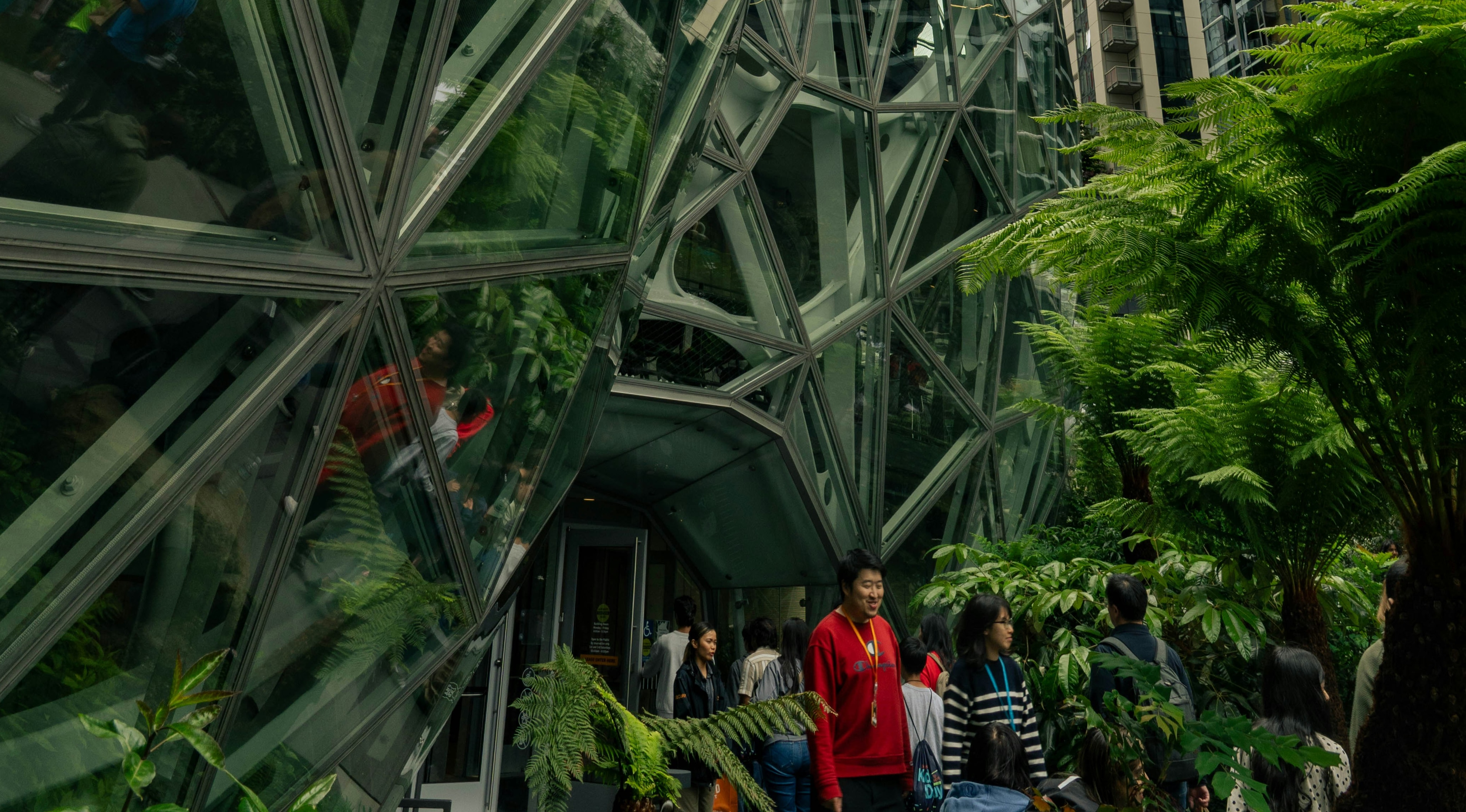 People walk out of a building with greenery: A new report finds leaders can translate sustainability into a competitive edge