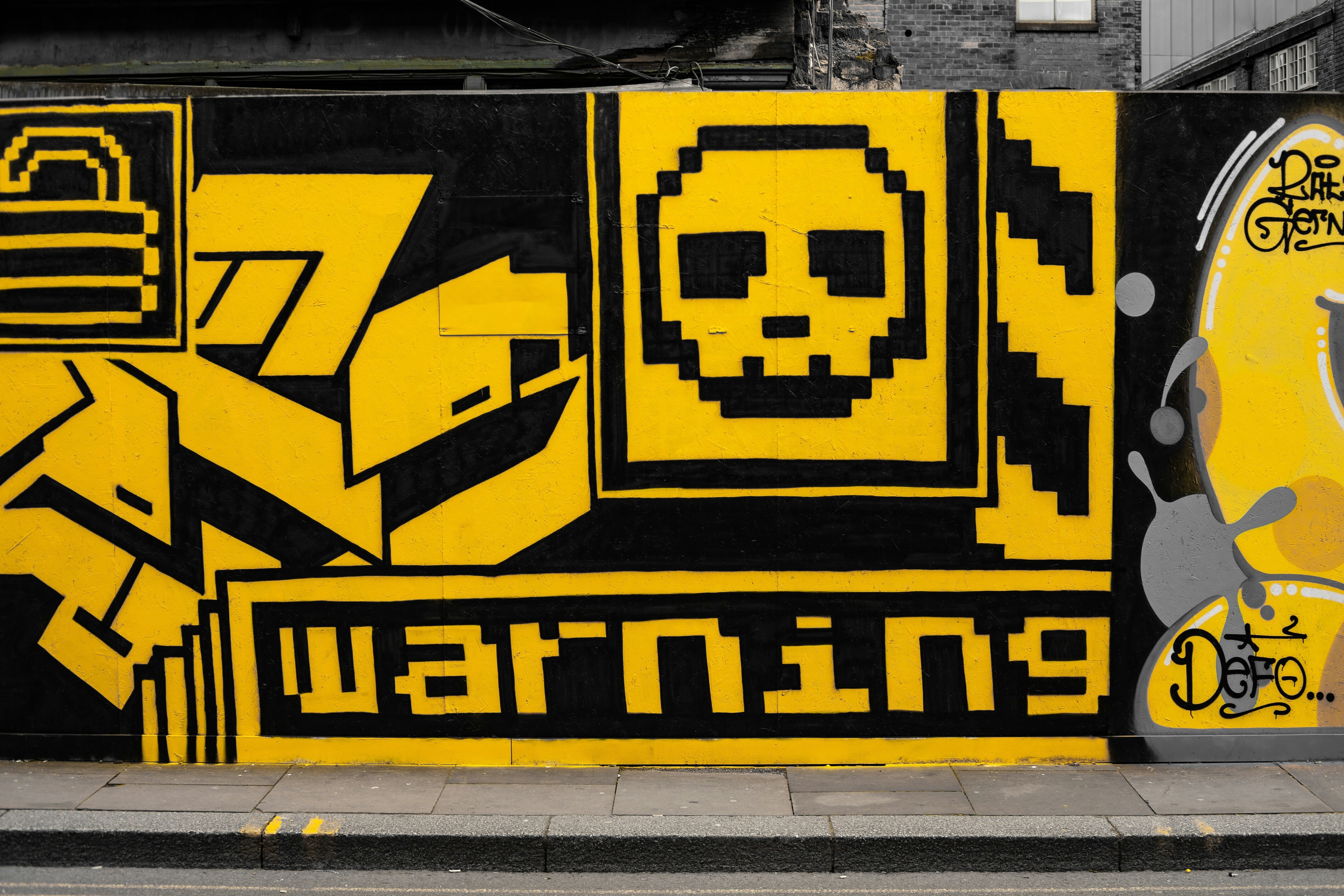 Black and yellow street art depicting a graphic skull and cross bones above the word warning: cybercrime