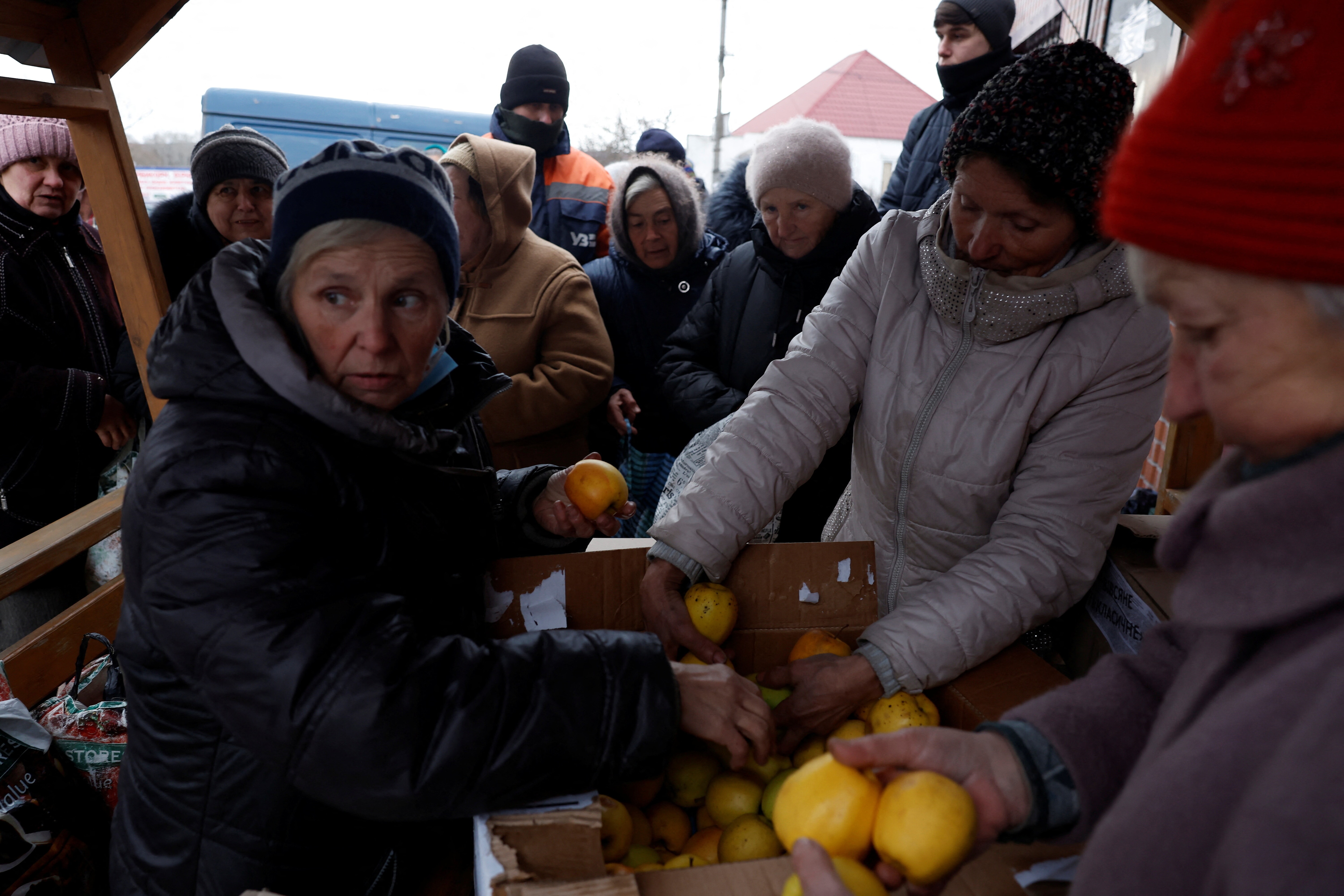 Women distribute apples and other humanitarian aid provided by the Ukrainian military for the villagers as Russia's attack on Ukraine continues, in Yampil, Ukraine, December 28, 2022.