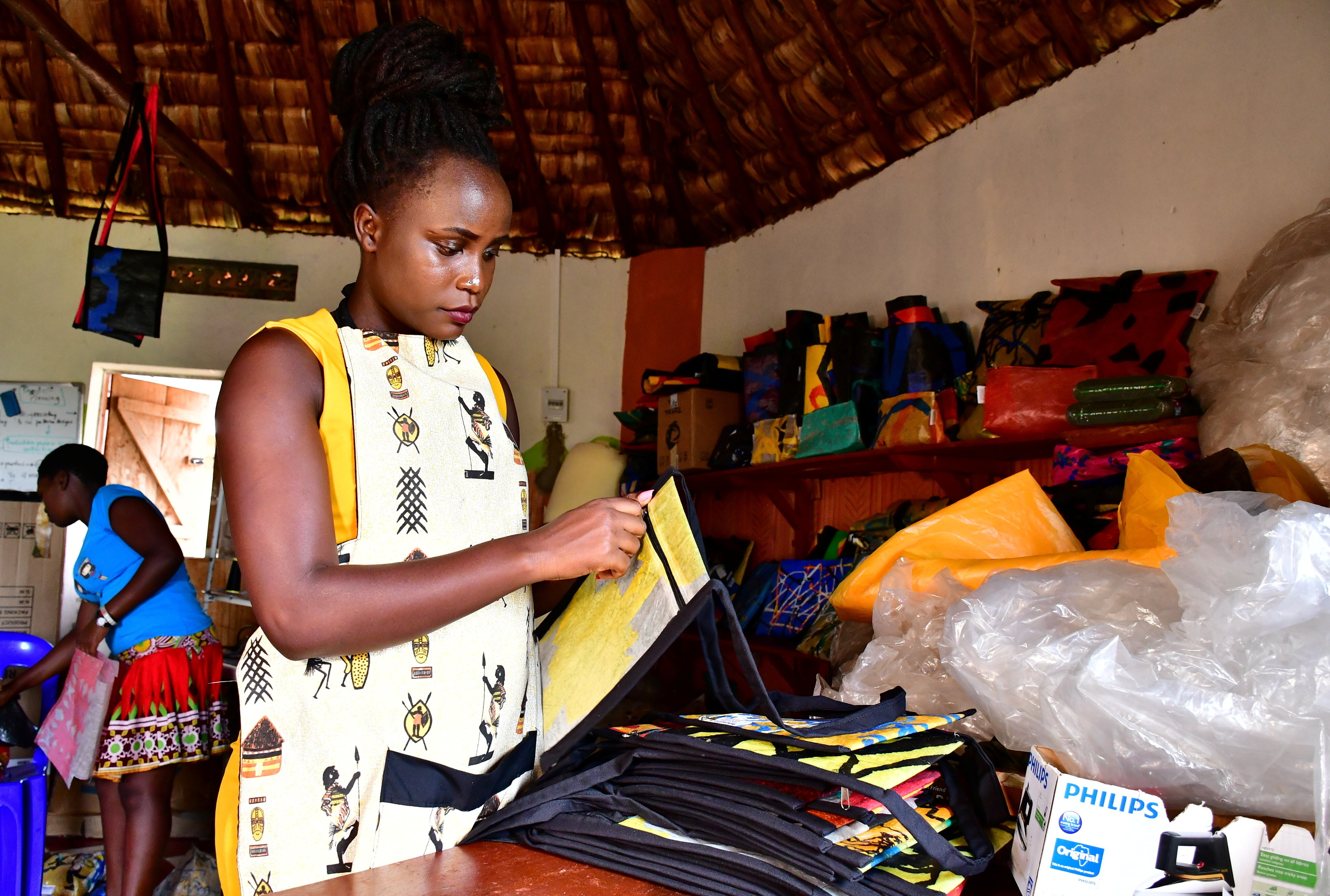 Ugandan 'wastepreneur' Faith Aweko checks a handbag made from transformed polythene waste.