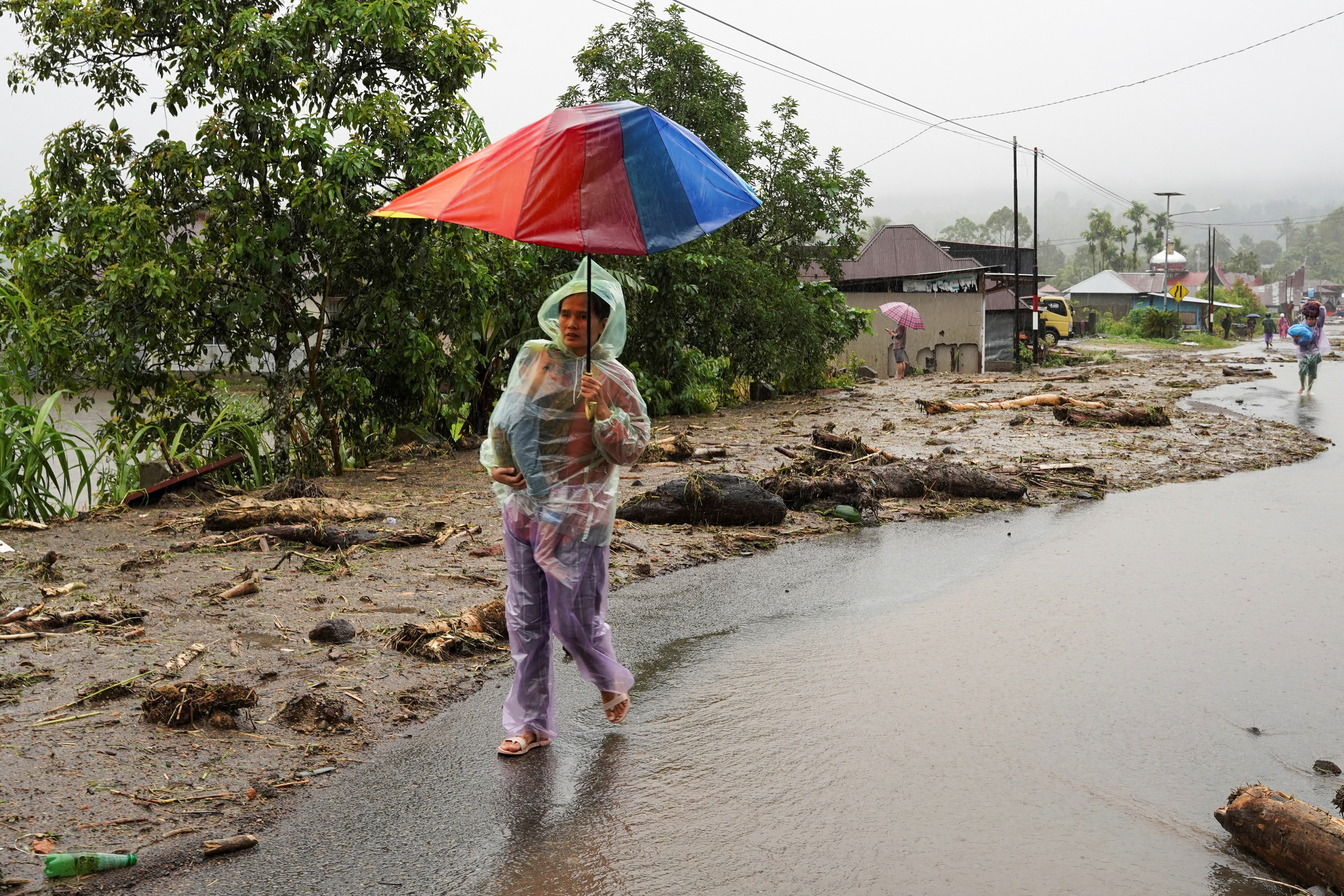 A woman walks with her child at an area hit by flash floods, following heavy rains in Malalak, Agam regency, West Sumatra province, Indonesia, November 27, 2025. REUTERS/Rafdi Rahmadi