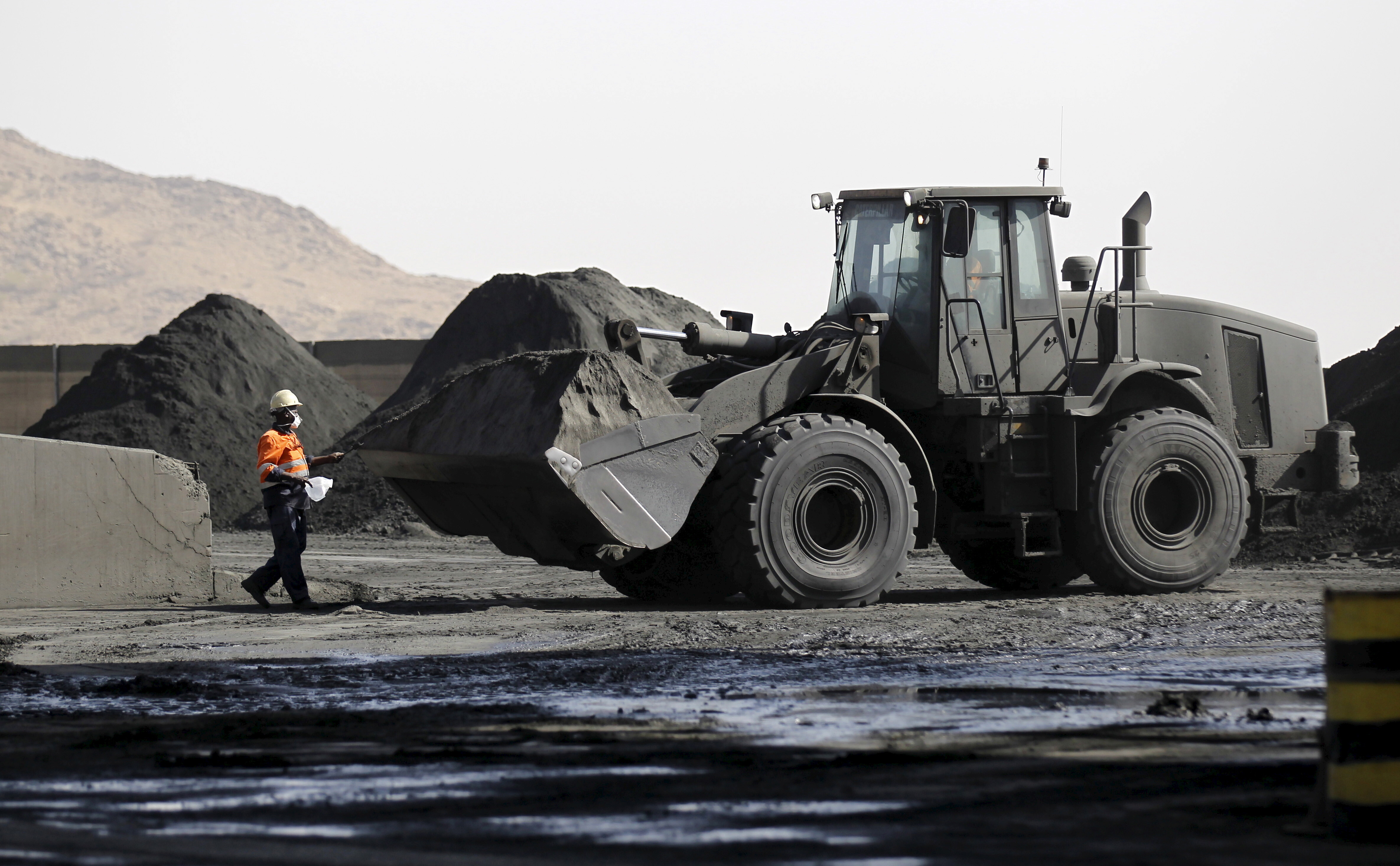 A worker collects samples for inspection from a pile of copper dust at a mine in Eritrea.