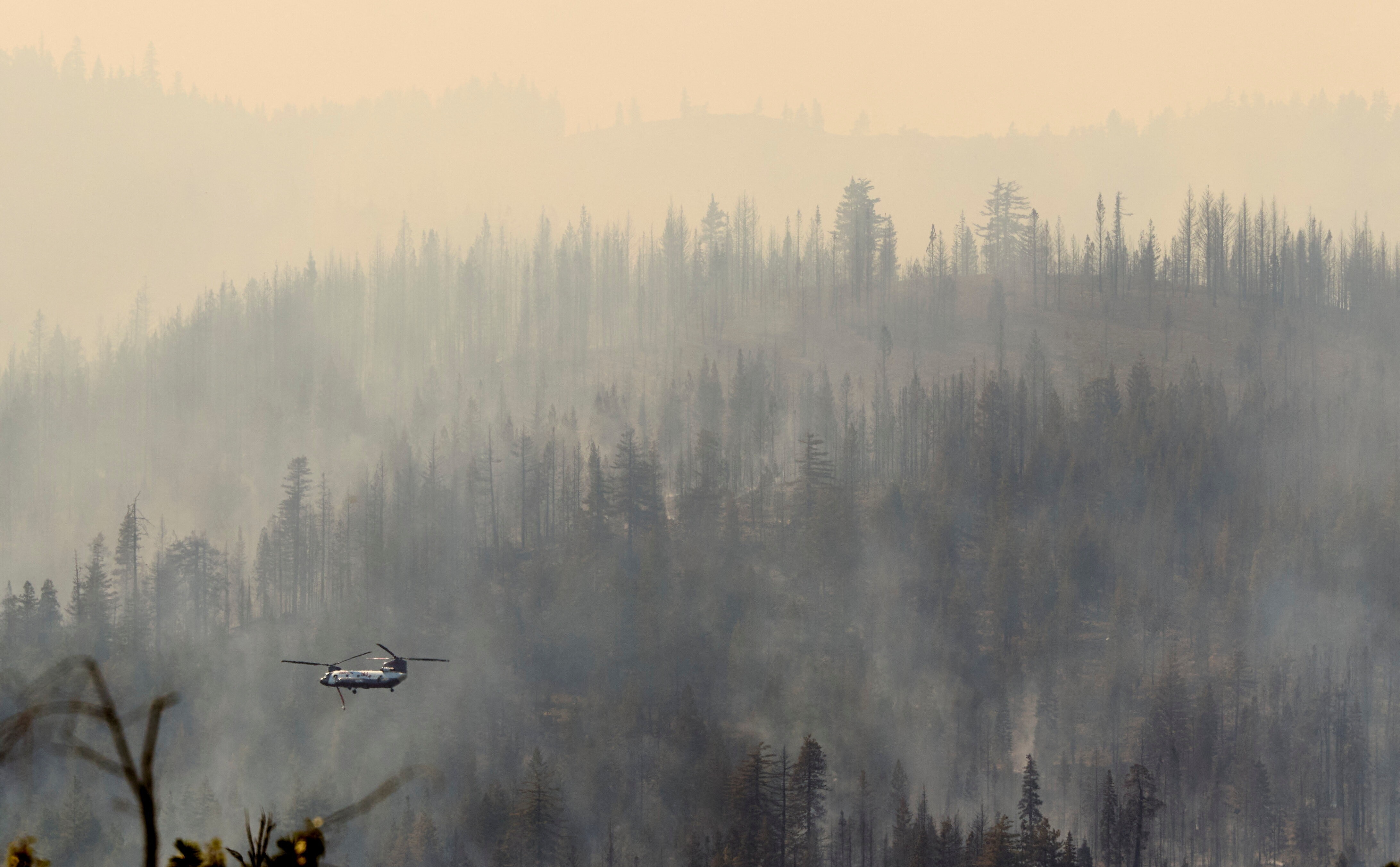A firefighting helicopter flies through the smoke from the Root Fire burning near Castle Crags State Park in Shasta County, California, U.S. September 2, 2025. The insurance sector has a crucial role to play in the fight against climate change.