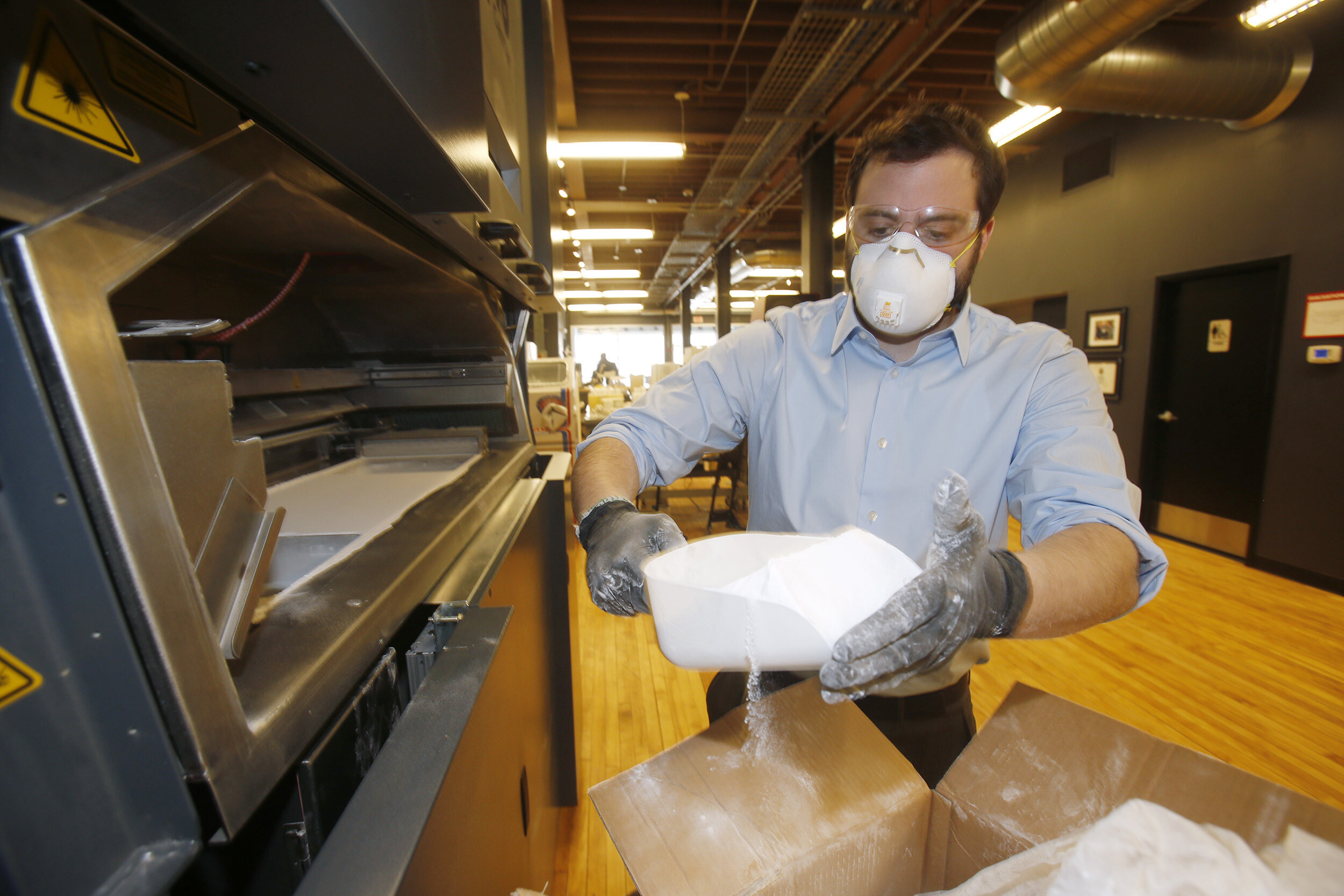 Intern Jim D'Andrea loads powdered nylon into a 3D Systems 3D printer at America Makes, the National Additive Manufacturing Innovation Institute in Youngstown, Ohio, March 5, 2014. Along the banks of the Mahoning River in the struggling Ohio steel town of Youngstown sits a once-abandoned furniture warehouse that has been converted into a sleek new laboratory. Inside is a Silicon Valley-style workspace complete with open meeting areas and colorful stools. Several 3-D printers hum in the background, while engineers type computer codes that tell the machines how to create objects by layering materials.