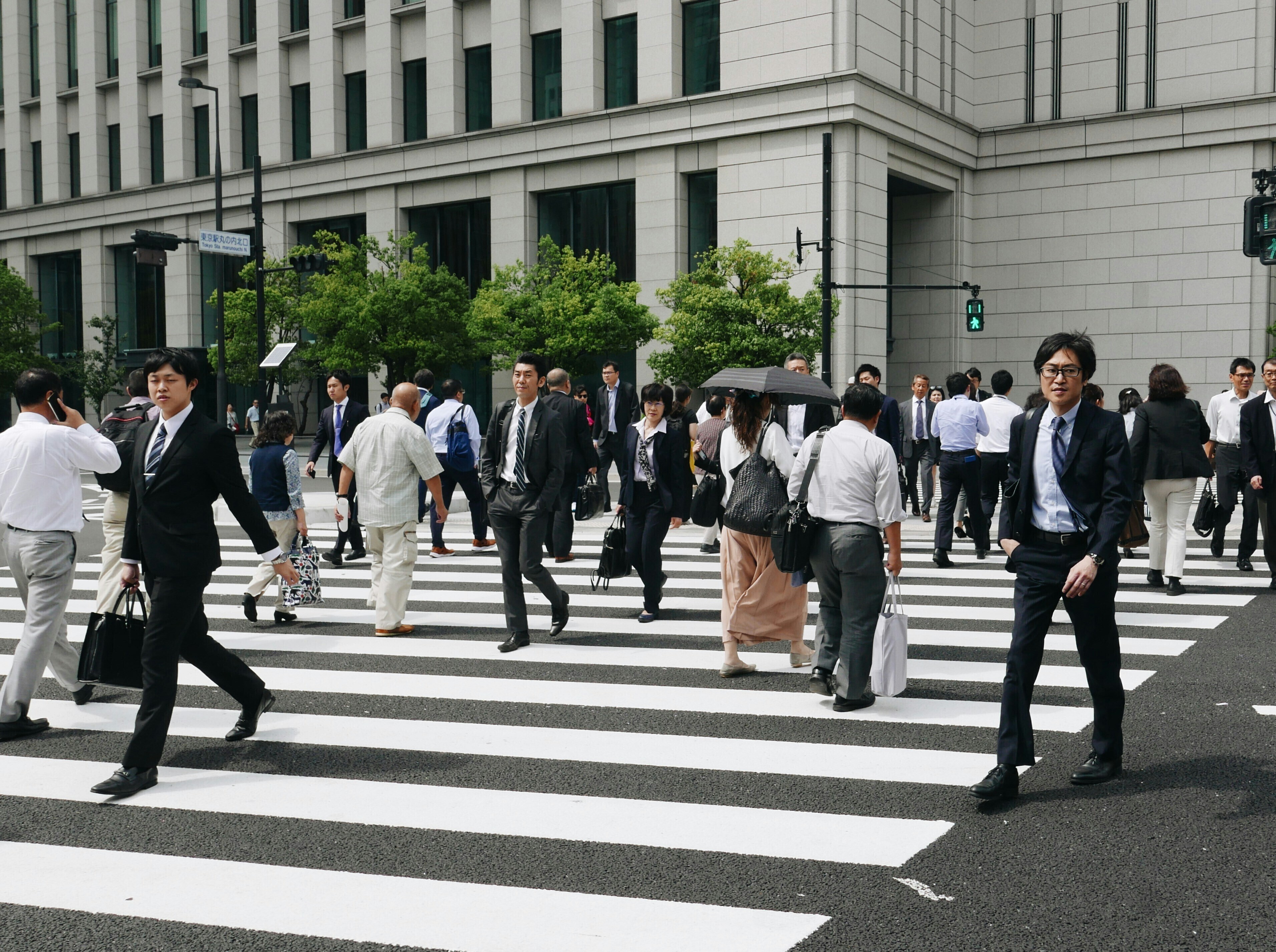 Hombres y mujeres de negocios caminando por un paso de peatones: en Japón crece el impulso hacia el apoyo a la andropausia.