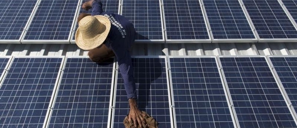 Francisco da Silva Vale, 61, cleans solar panels which power ice machines at Vila Nova do Amana community in the Sustainable Development Reserve, in Amazonas state, Brazil, September 22, 2015. Three solar-powered machines, are producing about ninety kilos of ice per day, in a region with poor access to electric energy, which used to be produced only with diesel oil, in the Amazon rain forest. The Gelo Solar (Solar Ice) project, developed by the Mamiraua Institute for Sustainable Development and the Sao Paulo University (USP), aims to improve the life quality of the residents of the communities allowing them to preserve their fish and fruits productions which are their main economic resources. The Mamiraua Institute is also using solar energy to supply the community's homes with water and light up a soccer field. 