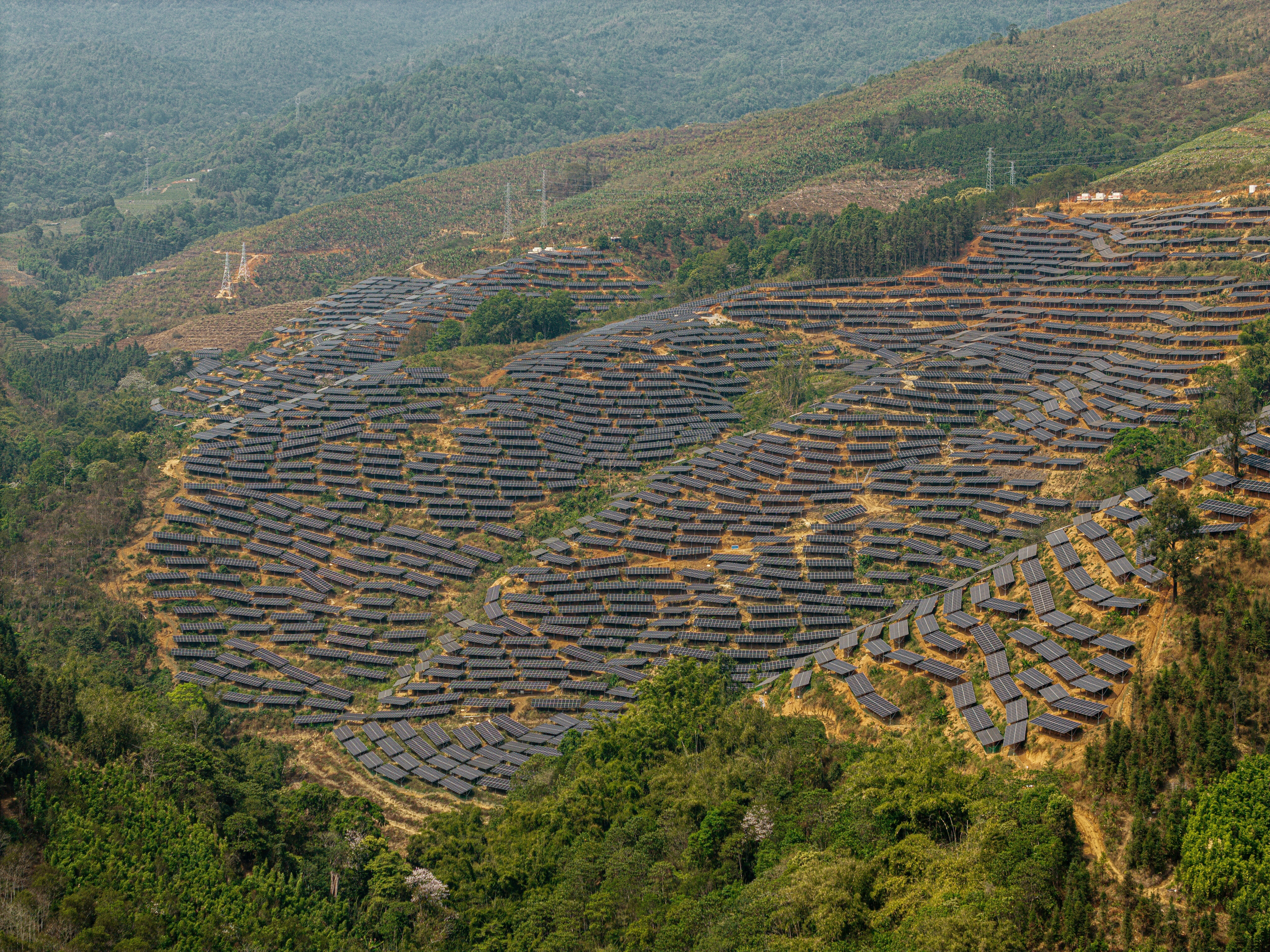 Solar panels with a backdrop of rolling green landscape in China, Yunnan, Kunming, Wuhua District.