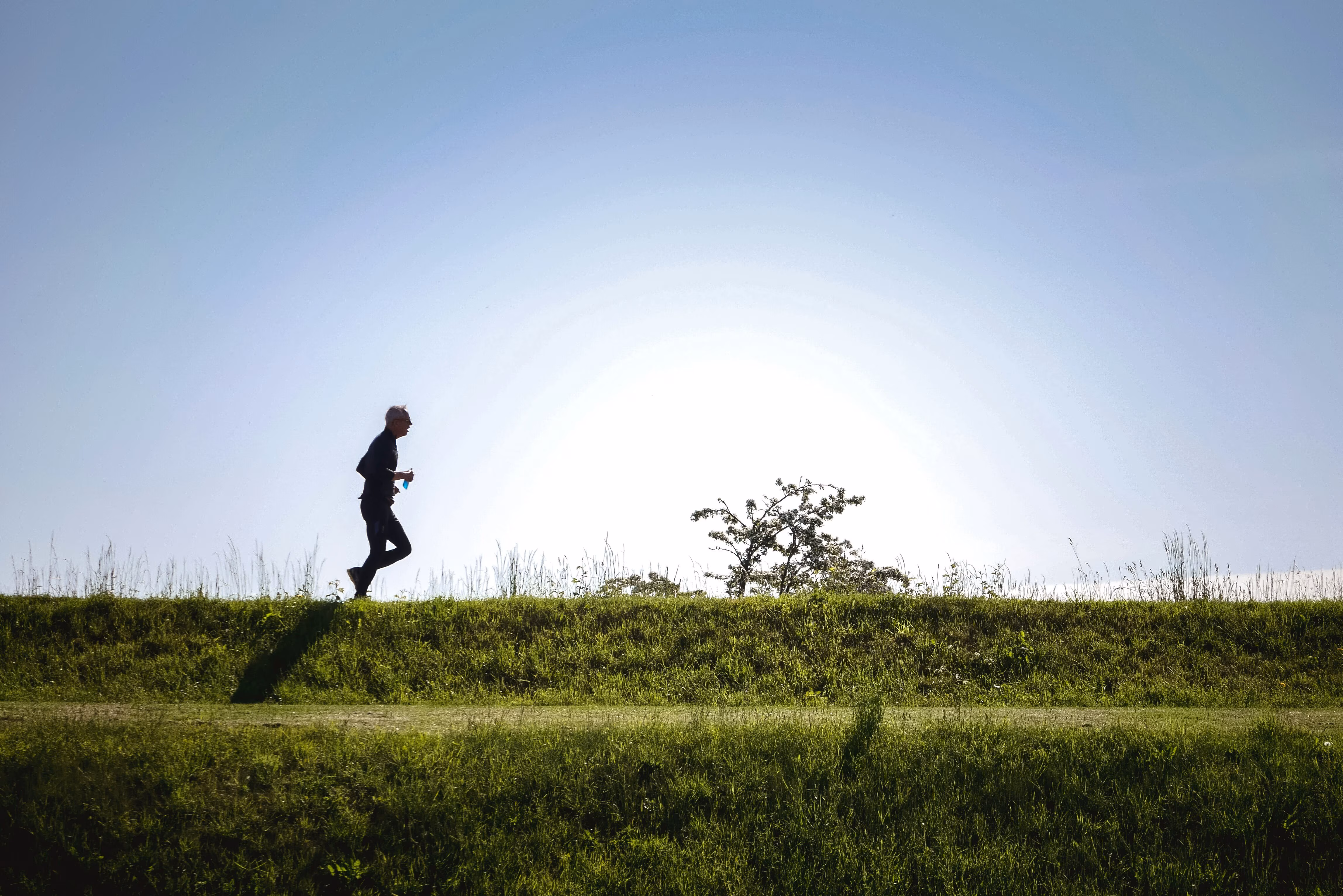 Un hombre corriendo por una colina con el sol bajo el horizonte.