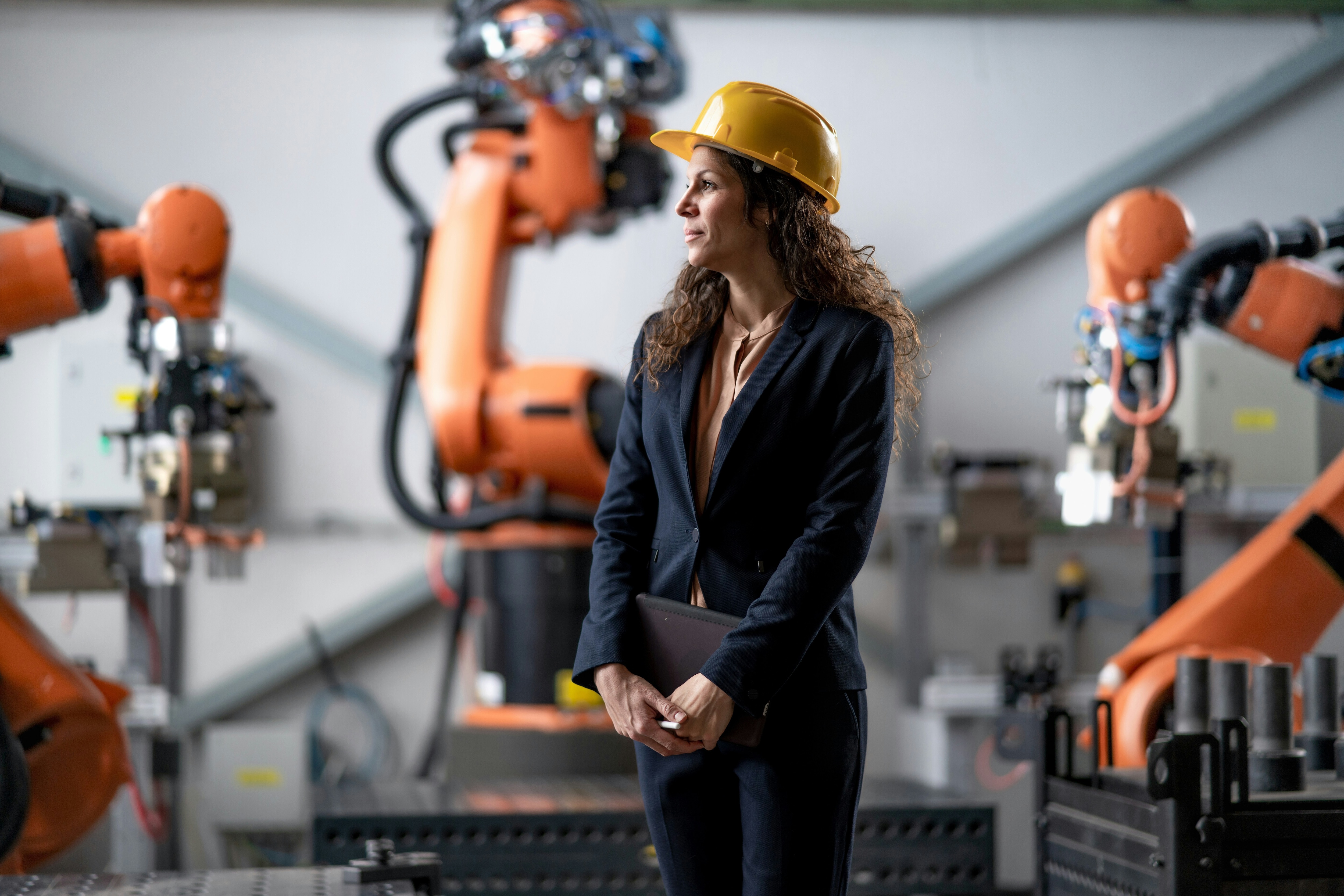 A woman in a hard hat and suit surrounded by an automation and robotics set up: Hard tech pilots typically fail at the decision layer but a better financing approach and model could resolve this