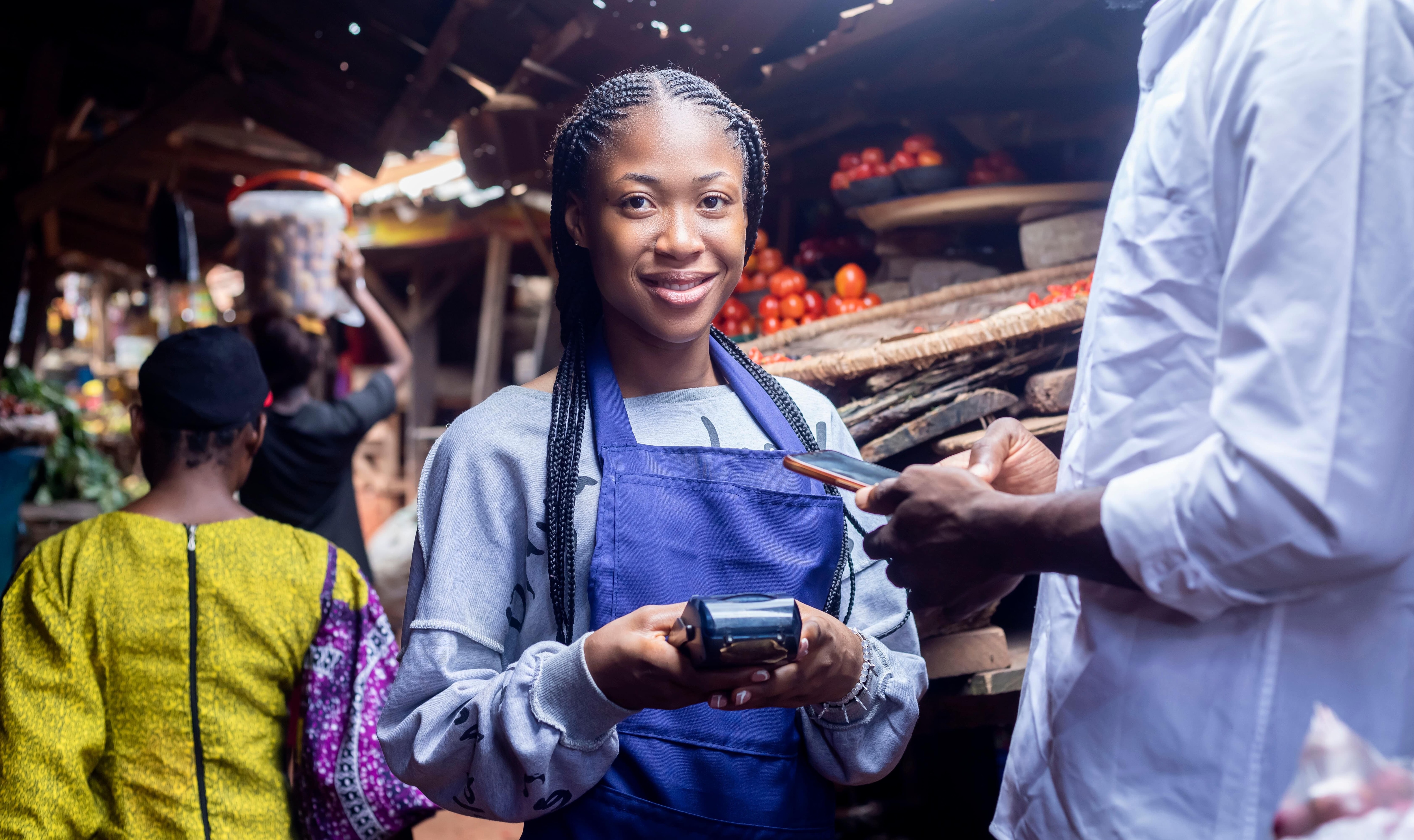 Young woman in Africa working for a small business takes digital payment from customer.