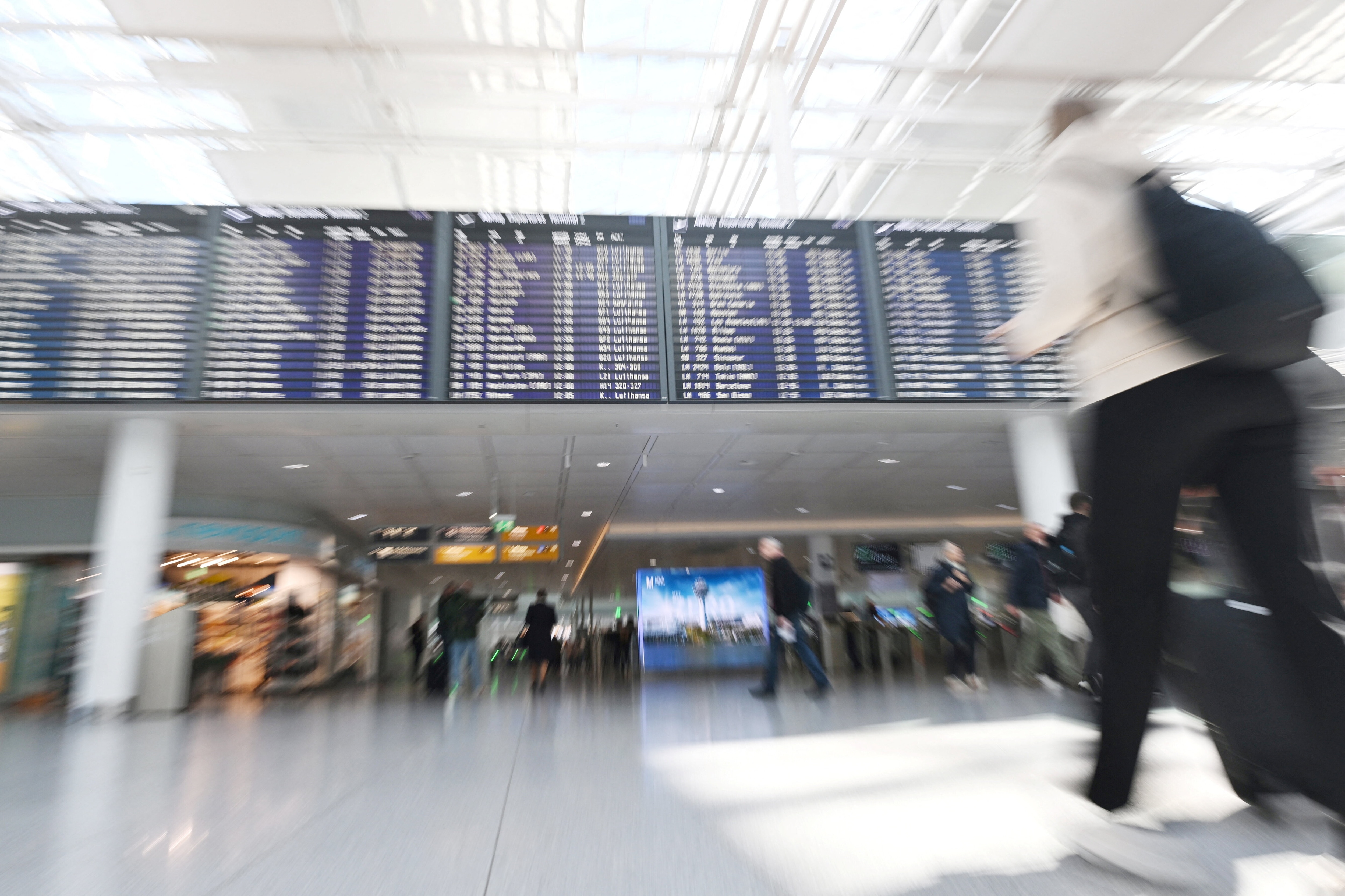 People walk a near display board at the airport in Munich, Germany, October 3, 2025. Munich airport reopened on Friday after shutting overnight due to drone sightings that forced the cancellation or diversion of dozens of flights on the eve of a national holiday and heightened concerns about the vulnerability of critical infrastructure in Europe. Picture taken with a zoom burst. REUTERS/Angelika Warmuth