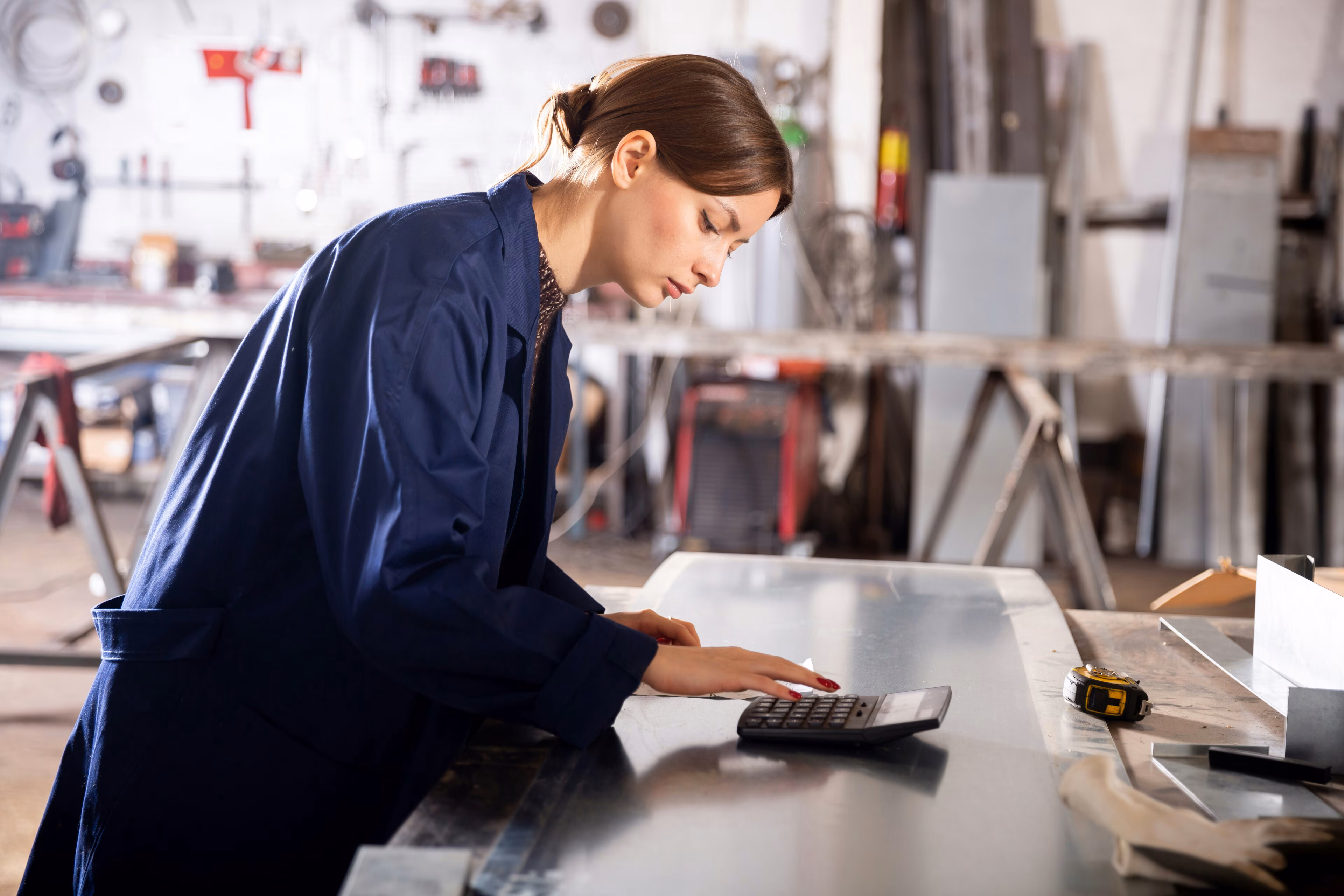 Mujer con overol usa calculadora: La transformación en la industria manufacturera a menudo fracasa debido a la mala comunicación