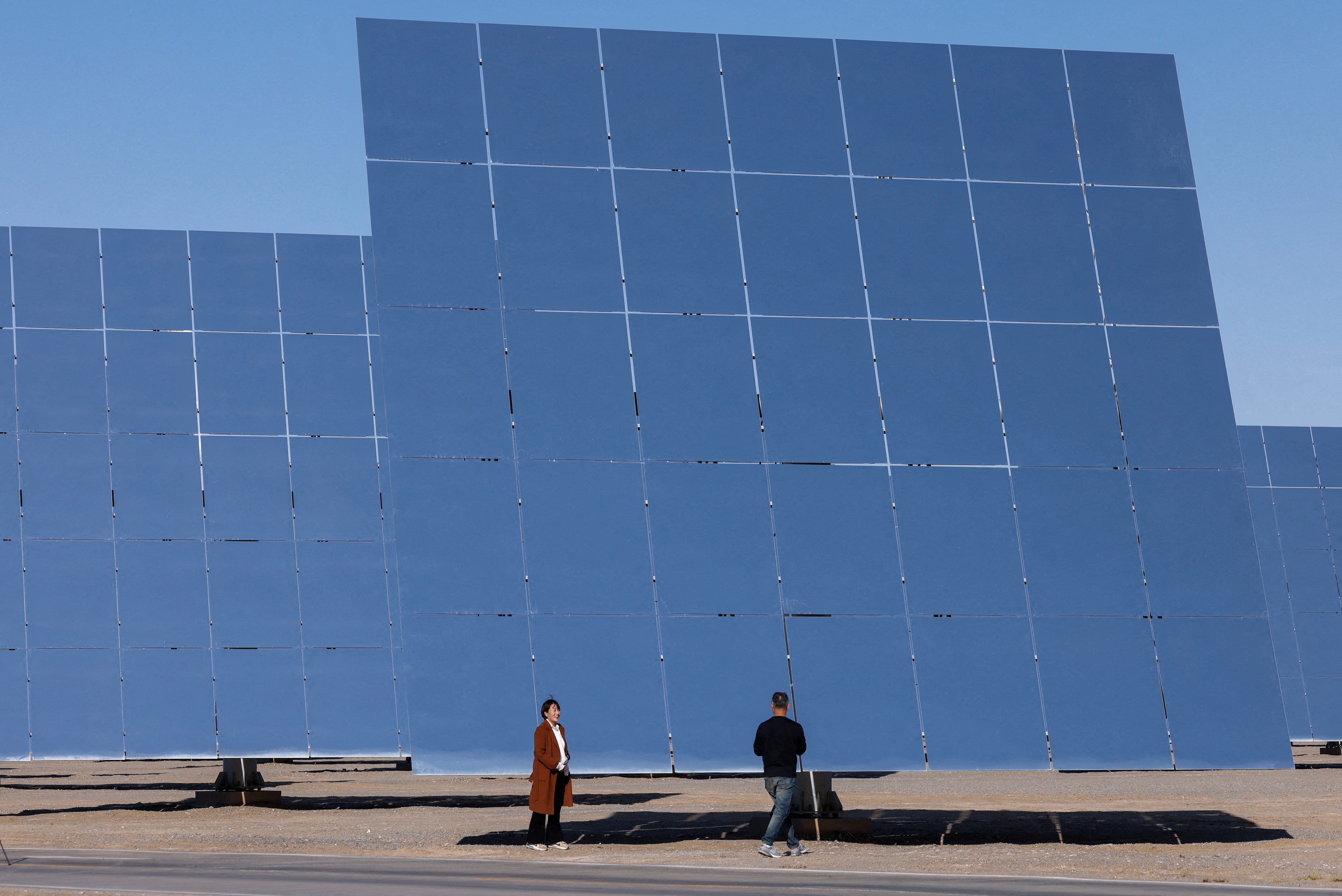  Journalists work next to heliostat mirrors at the site of Dunhuang Shouhang 100MW Tower Solar Thermal Power Generation Project, during an organised media tour to Dunhuang Photovoltaic Industrial Park, in Gansu province, China October 16, 2024: Venture captial has brought hardtech innovation but asset-based finance could scale it up