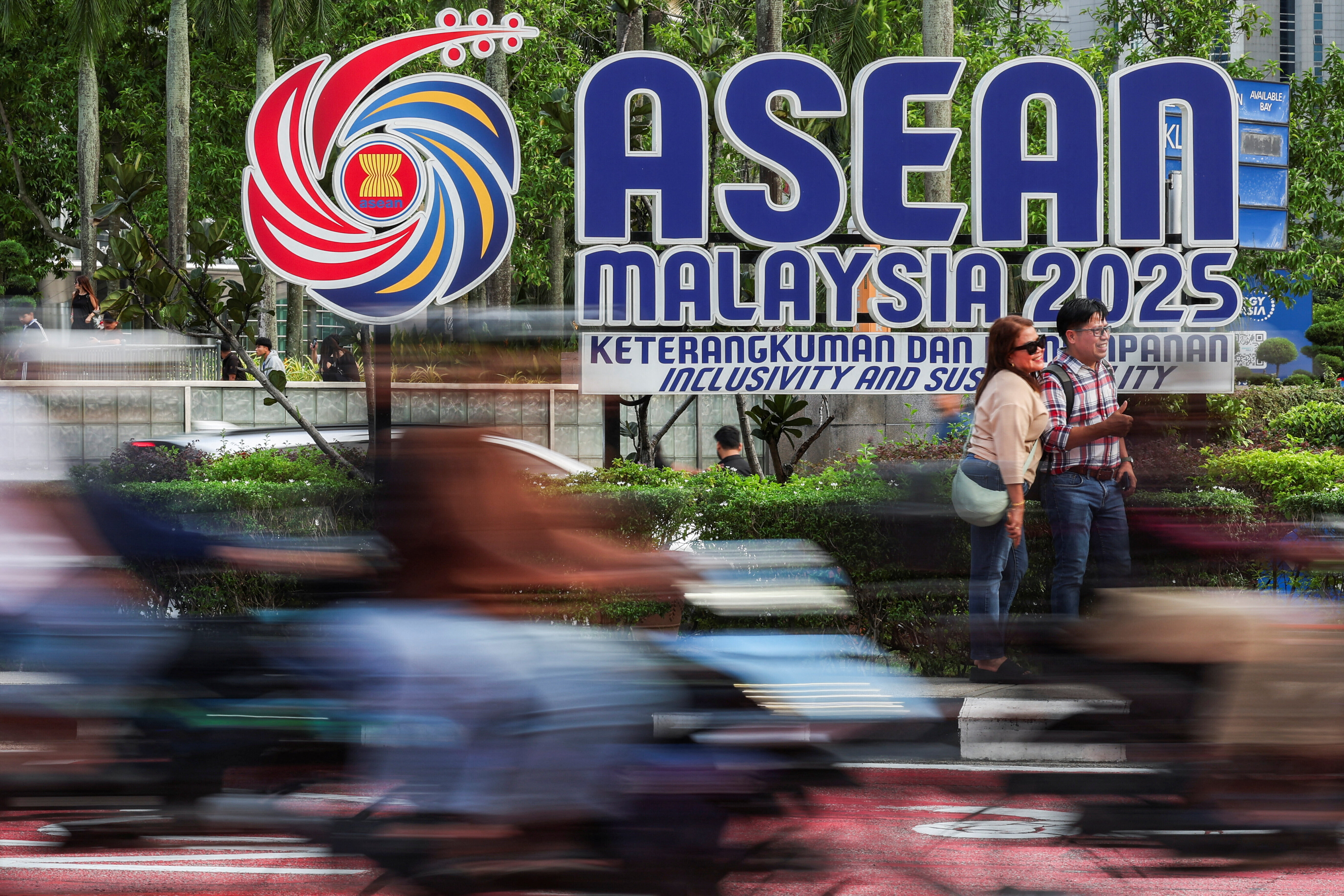 2025年10月24日、マレーシアのクアラルンプールで開催された第47回ASEAN首脳会議を前に、ASEANのロゴマークの横で記念写真を撮る人々。
