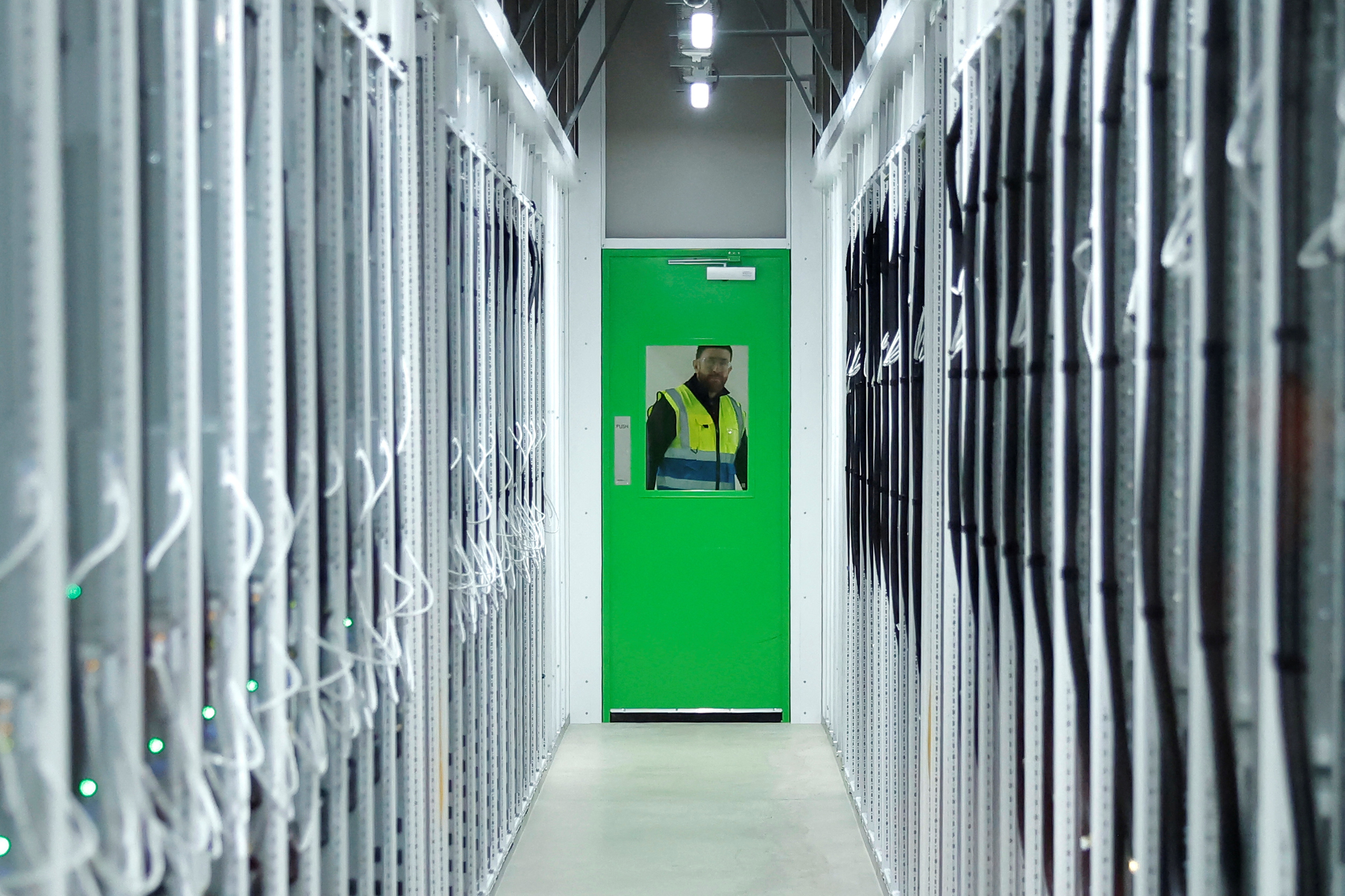 A Microsoft employee looks through a hot room window in the Microsoft cloud data hall at the Microsoft data centre during an announcement on its global energy strategy, regarding how it procures and manages energy to scale AI and digital infrastructure sustainably, in Dublin, Ireland, February 17, 2026.