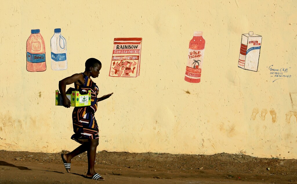A woman counts her change as she leaves a convenience store in South Africa