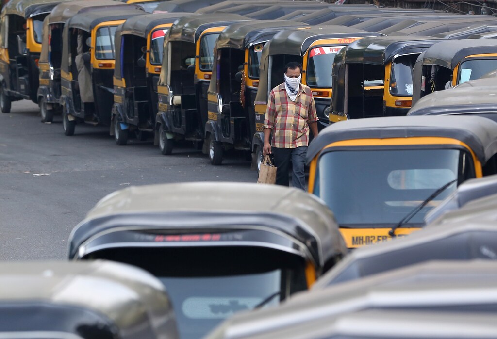 A man wearing a handkerchief as a mask moves past parked autorickshaw during a curfew to limit the spreading of coronavirus disease (COVID-19), in Mumbai, India, March 24, 2020. REUTERS/Prashant Waydande - RC29QF9NTAXU
