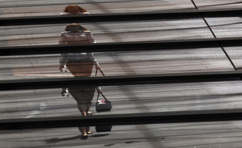 An office worker with a shopping bag is reflected on the roof of a building in central Sydney February 5, 2013. Picture rotated 180 degrees. Australia's central bank kept its main cash rate steady at a record-matching low of 3.0 percent on Tuesday, a widely expected decision given how the global background had brightened since its last easing in December. REUTERS/Daniel Munoz (AUSTRALIA - Tags: BUSINESS TPX IMAGES OF THE DAY) - GM1E9250X6201