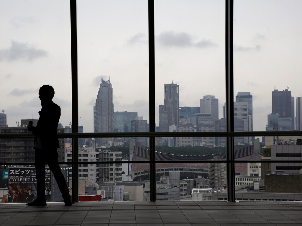 A man is silhouetted in front of Tokyo's skyscrapers in Tokyo, Japan June 30, 2017. REUTERS/Kim Kyung-Hoon - RTS197HQ