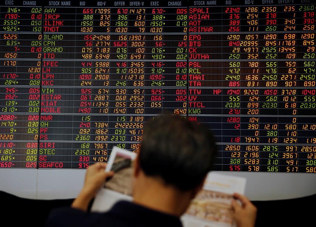 A man reads a magazine in front of a stock index board at a bank in Bangkok, Thailand October 17, 2016. REUTERS/Edgar Su - RTX2P3YN