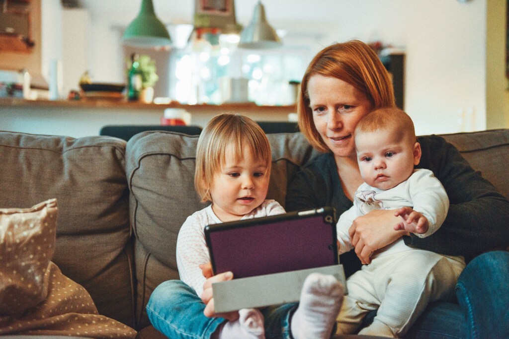 A mother and her children play with a tablet.