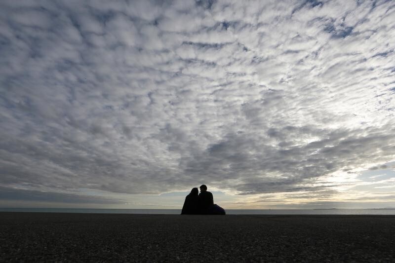 A couple is seen in silhouette under a partly cloudy sky as they sit along the Mediterranean Sea beach front on the Promenade Des Anglais in Nice December 2, 2014. REUTERS/Eric Gaillard (FRANCE - Tags: ENVIRONMENT SOCIETY) - PM1EAC219F401