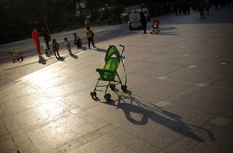 A baby stroller is seen as mothers play with their children at a public area in downtown Shanghai November 19, 2013. China will further ease its family planning laws after announcing last week that it would allow millions of families to have two children, a senior official from the government's family planning commission said on Tuesday. REUTERS/Carlos Barria