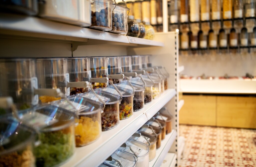 Close-up of various food items in jars on display rack at illuminated at zero waste store