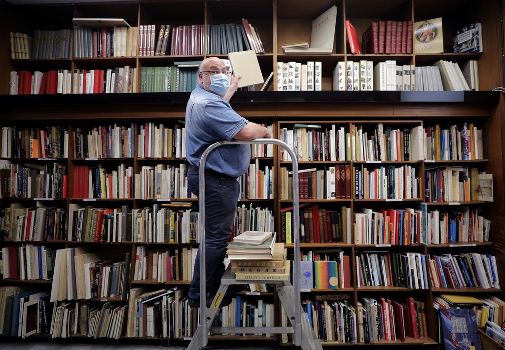 El librero Philippe Seyrat, con una máscara facial protectora, coloca libros en la librería La Sorbona de Niza mientras Francia suaviza sus estrictas reglas de cierre durante el brote de la enfermedad coronavirus (COVID-19) en Francia, el 13 de mayo de 2020.