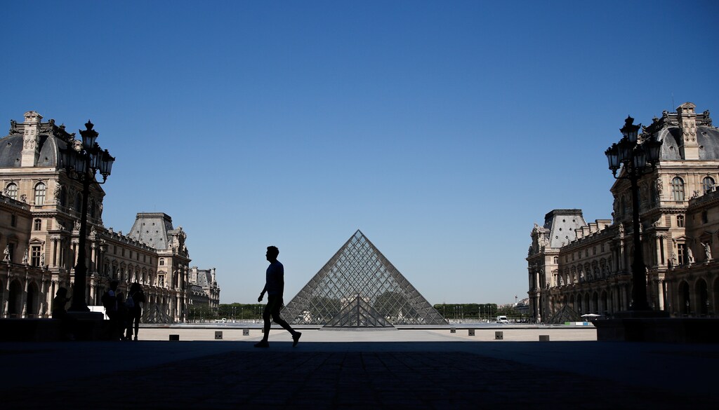 A man walks near the Louvre Pyramid