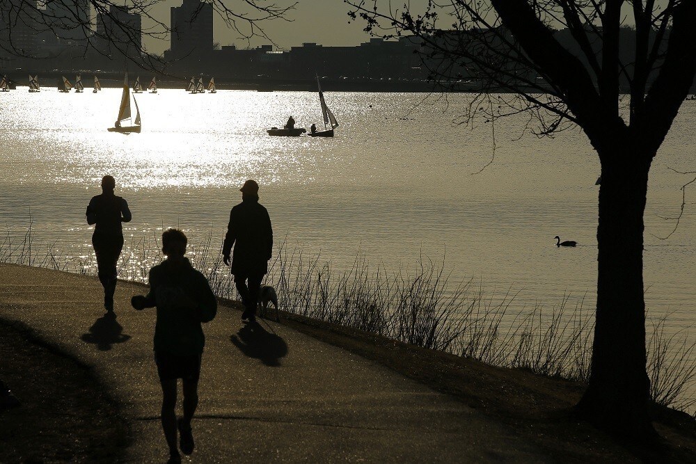 Joggers run past sailboats on the Charles River on an early spring evening in Boston, Massachusetts April 3, 2014. REUTERS/Brian Snyder (UNITED STATES - Tags: SOCIETY ENVIRONMENT) - RTR3JV6P