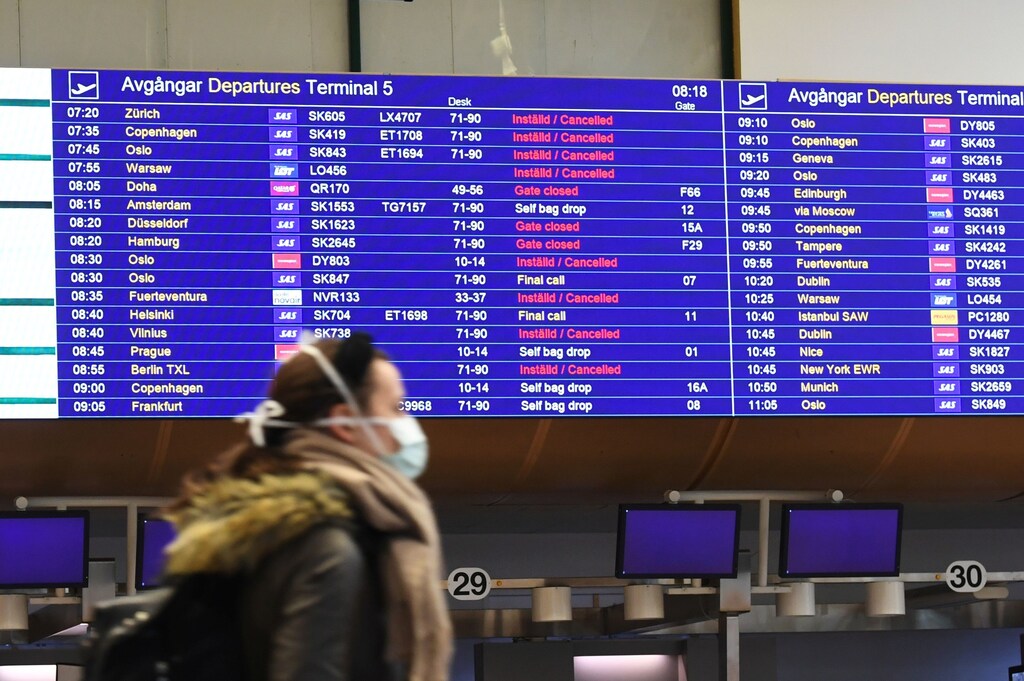 A passenger wears a protective face mask as she passes in front of a departures boards at Arlanda International Airport, near Stockholm, Sweden March 16, 2020. TT News Agency/Fredrik Sandberg via REUTERS ATTENTION EDITORS - THIS IMAGE WAS PROVIDED BY A THIRD PARTY. SWEDEN OUT. NO COMMERCIAL OR EDITORIAL SALES IN SWEDEN. - RC2YKF9Y4IJ1
