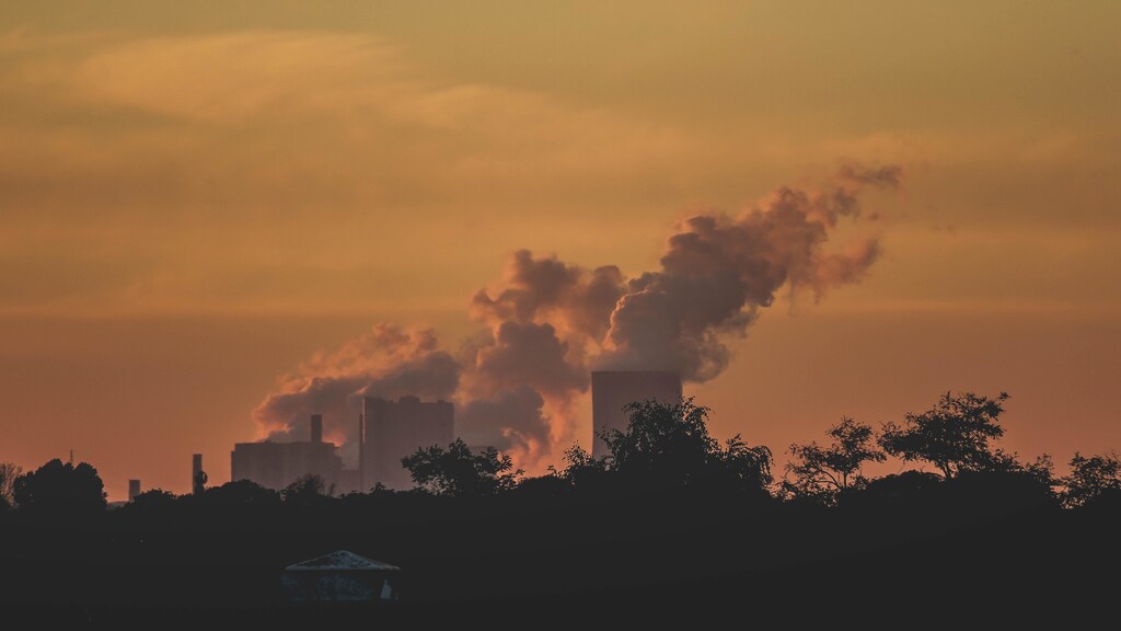 Multiple buildings polluting atmosphere behind trees. Air pollution affects 90% of the world's population.