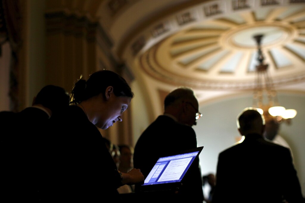 A journalist take notes on her laptop as U.S. Senate Minority Leader Harry Reid (D-NV) (R) talks to reporters during a new conference following party policy lunch meeting at the U.S. Capitol in Washington August 4, 2015. REUTERS/Carlos Barria - RTX1N22F