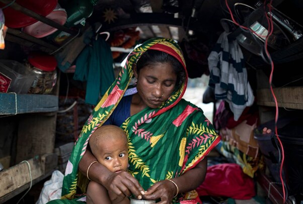 Jahanara Begum, a member of the Manta community, sits with her child on the boat they call home, on the Meghna river in Lakshmipur District, Bangladesh.