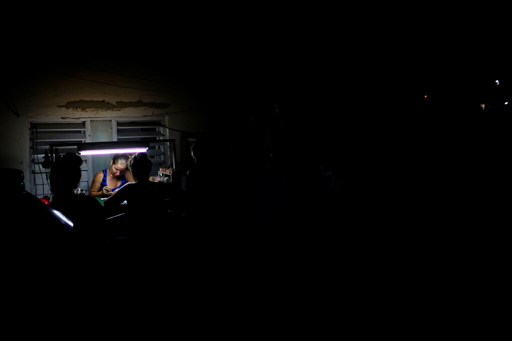Self-employed Roxana Dias works on her porch late at night in Havana, Cuba, August 5, 2017. Picture taken August 5, 2017. REUTERS/Alexandre Meneghini - RC1CD56A73B0