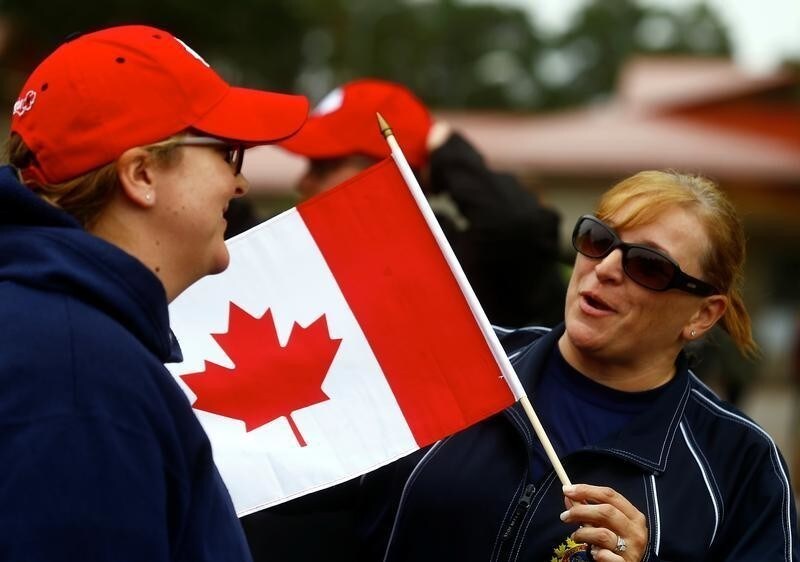 A woman holds a flag as Canadian-led NATO Enhanced Forward Presence battlegroup soldiers celebrate the 150th anniversary of the Confederation on Canada Day at Adazi Military Base, Latvia