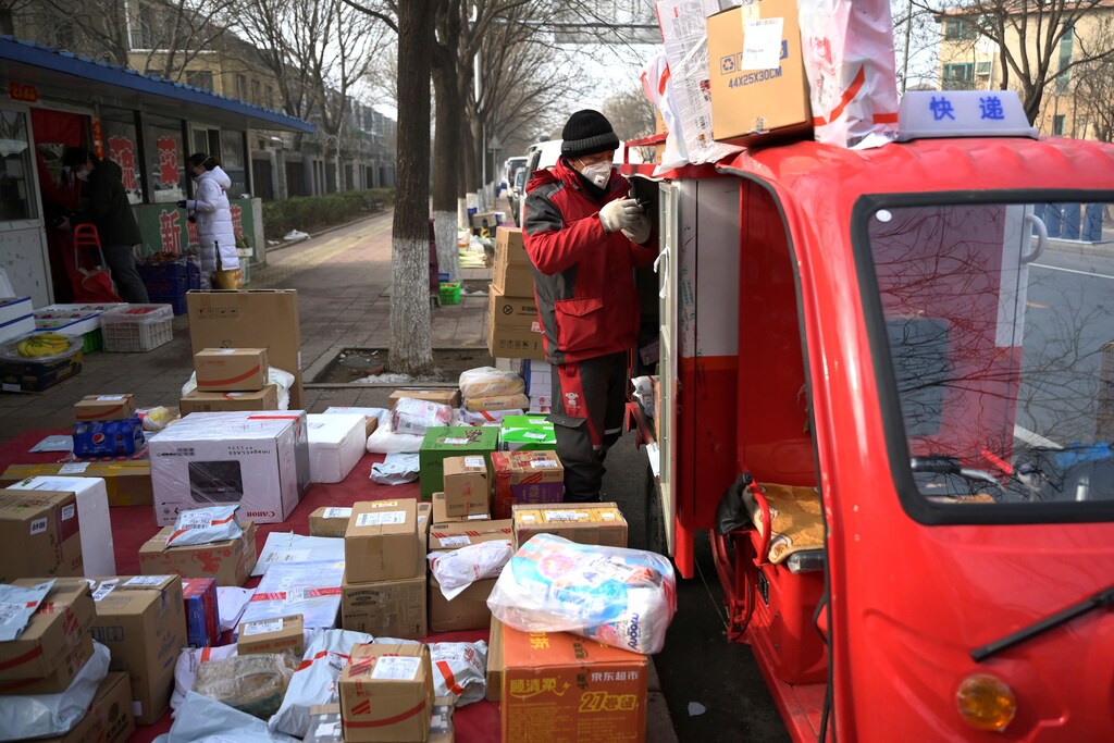 A JD.com delivery worker wearing a face mask unloads parcels outside a residential compound, as the country is hit by an outbreak of the novel coronavirus, in Beijing, China February 21, 2020. REUTERS/Tingshu Wang - RC2X4F99JTNL