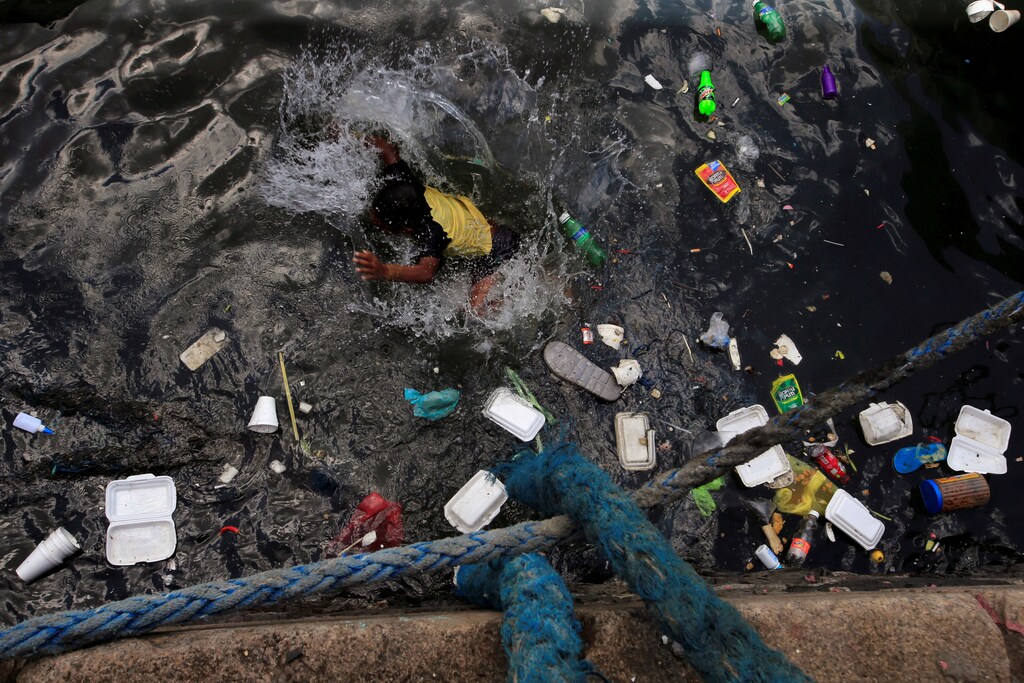 A boy swims in the polluted waters of the Manila bay to cool off from the intense heat within the slum area of the Baseco compound in Tondo, metro Manila, Philippines April 30, 2018. REUTERS/Romeo Ranoco - RC17978C2A20