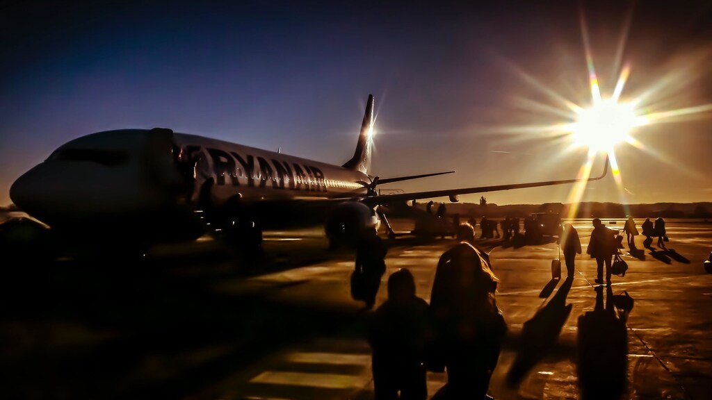 People walking towards an aeroplane at sunset.