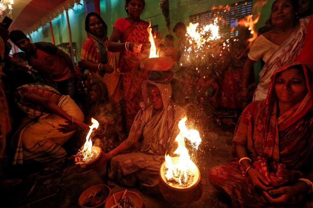 A woman holds earthen pots with fire during a ritual while worshipping Sheetala Mata, the Hindu goddess of smallpox, during Sheetala Puja in which devotees pray for the betterment of their family and society, in Kolkata, India, March 28, 2019. REUTERS/Rupak De Chowdhuri - RC187A814790