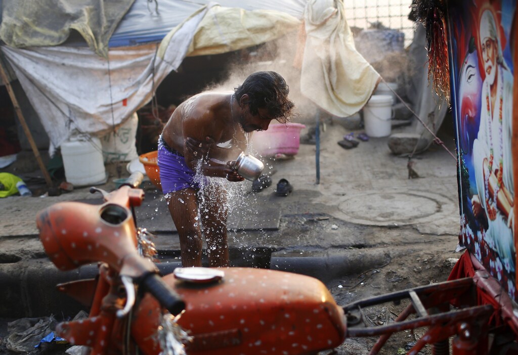 A migrant laborer bathes near a hotel construction site on a cold winter morning in New Delhi