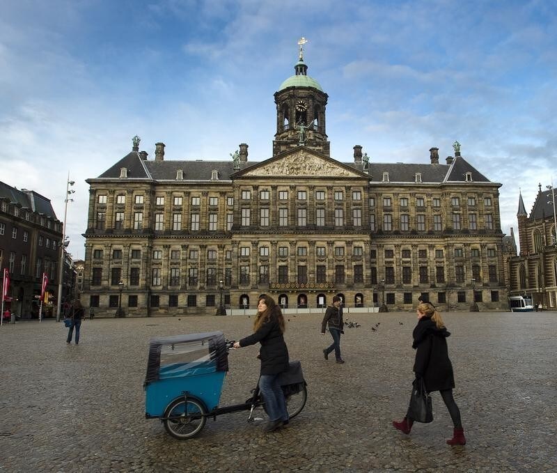 People walk past the Royal Palace on Dam Square, where Dutch Queen Beatrix will sign her abdication in favor of her son Prince Willem-Alexander, in Amsterdam January 29, 2013. Queen Beatrix, who turns 75 on Thursday, announced she was abdicating in favour of her son, Prince Willem-Alexander, telling her country it was time to hand the crown to the next generation after more than three decades on the throne. REUTERS/Toussaint Kluiters/United Photos (NETHERLANDS - Tags: ROYALS POLITICS ENTERTAINMENT) - GM1E91U01HX01