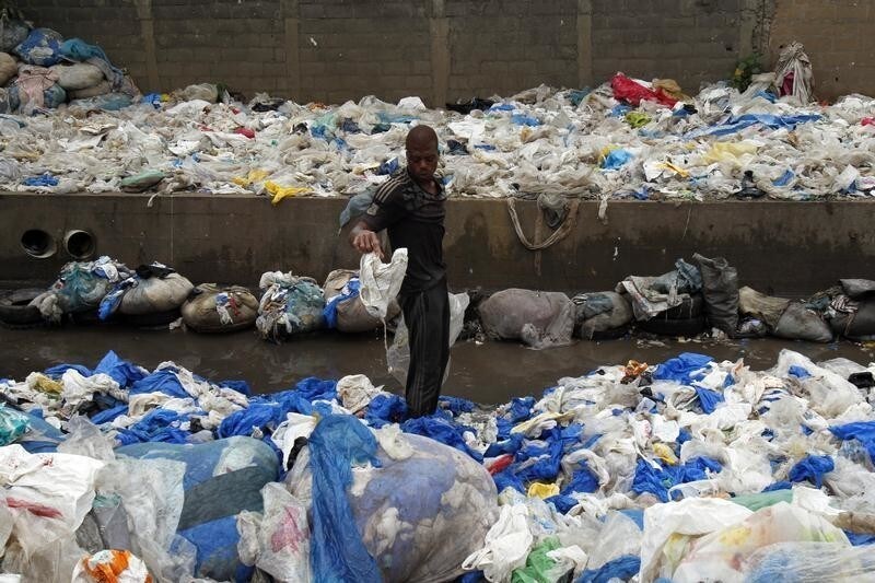 A man gathers plastic for recycling in the Yopougon area of Abidjan September 10, 2013. Ivorian authorities have decided to ban the production, use and commercialization of plastic bags by the end of the year.