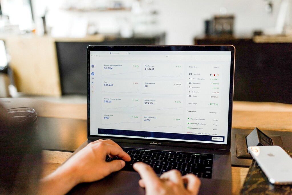 a man types on his laptop, on the screen different charts relating to money are shown