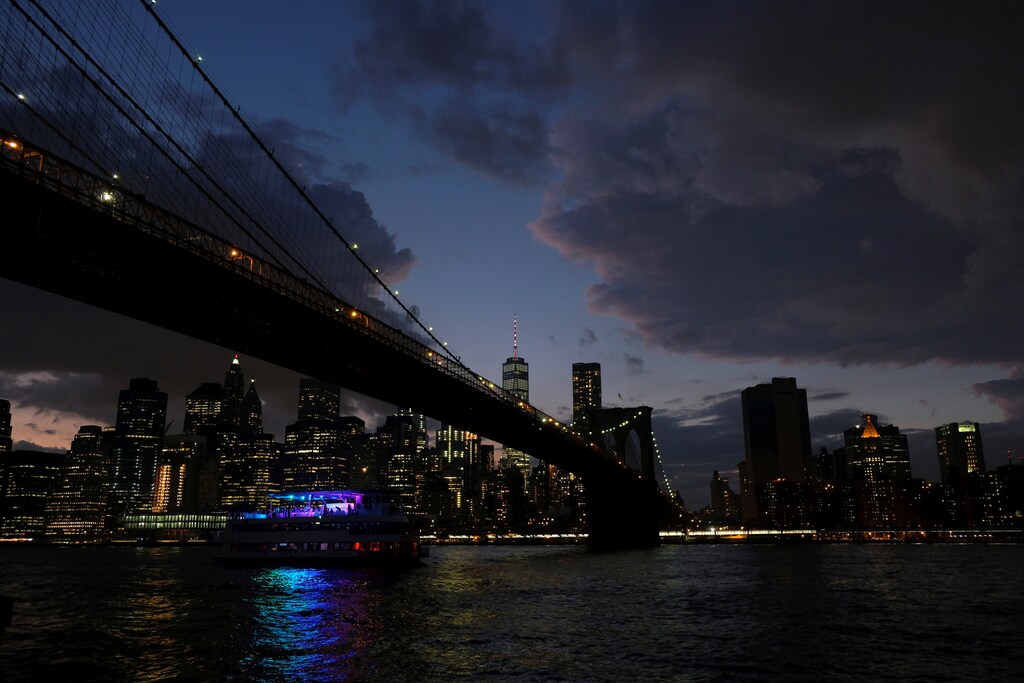A ferry boat passes under Brooklyn Bridge in front of the night skyline of Lower Manhattan in New York City, U.S., at dusk, September 15, 2017. REUTERS/Darrin Zammit Lupi - RC1252C64BA0